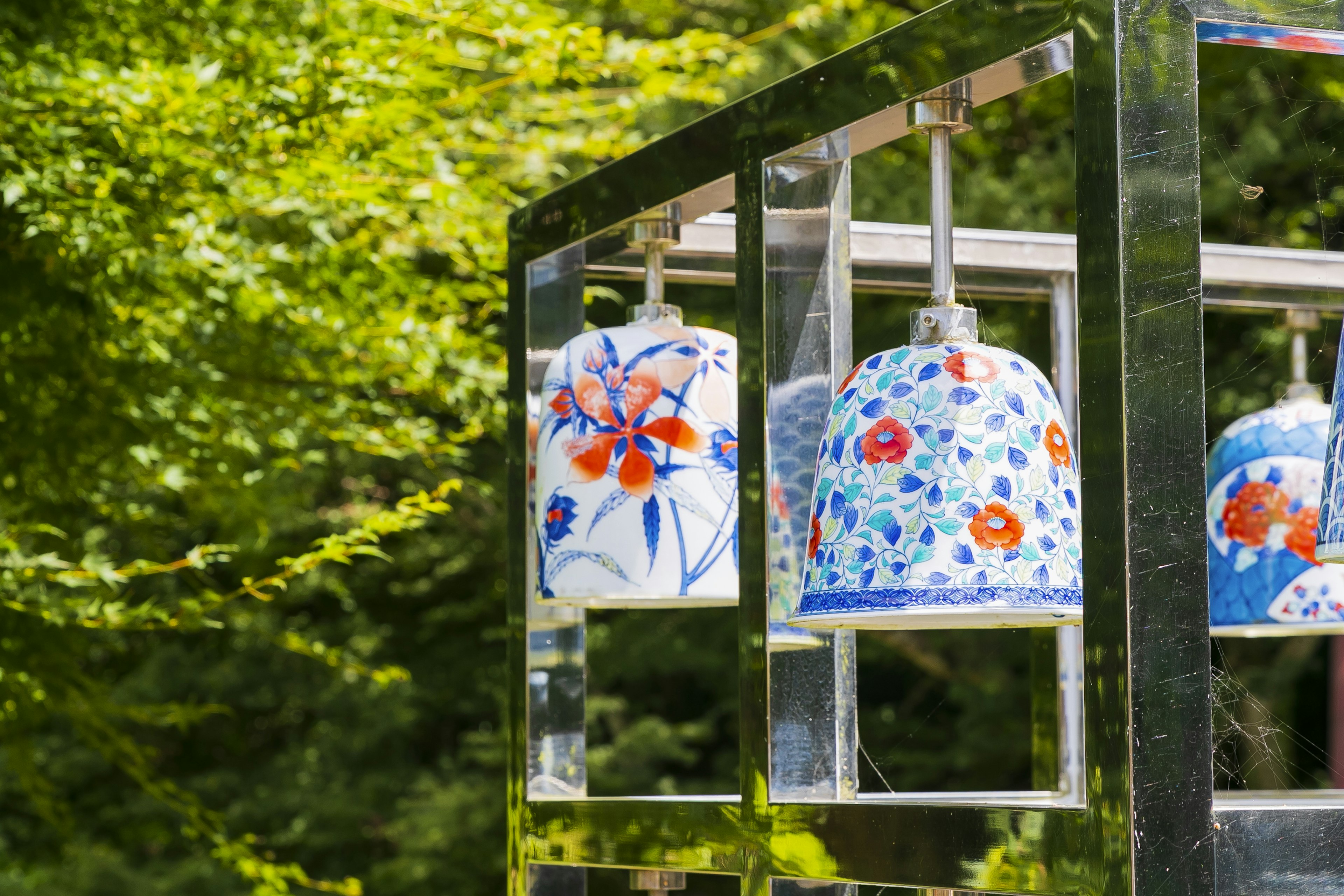 Colorful flower-patterned wind chimes hanging against a green background