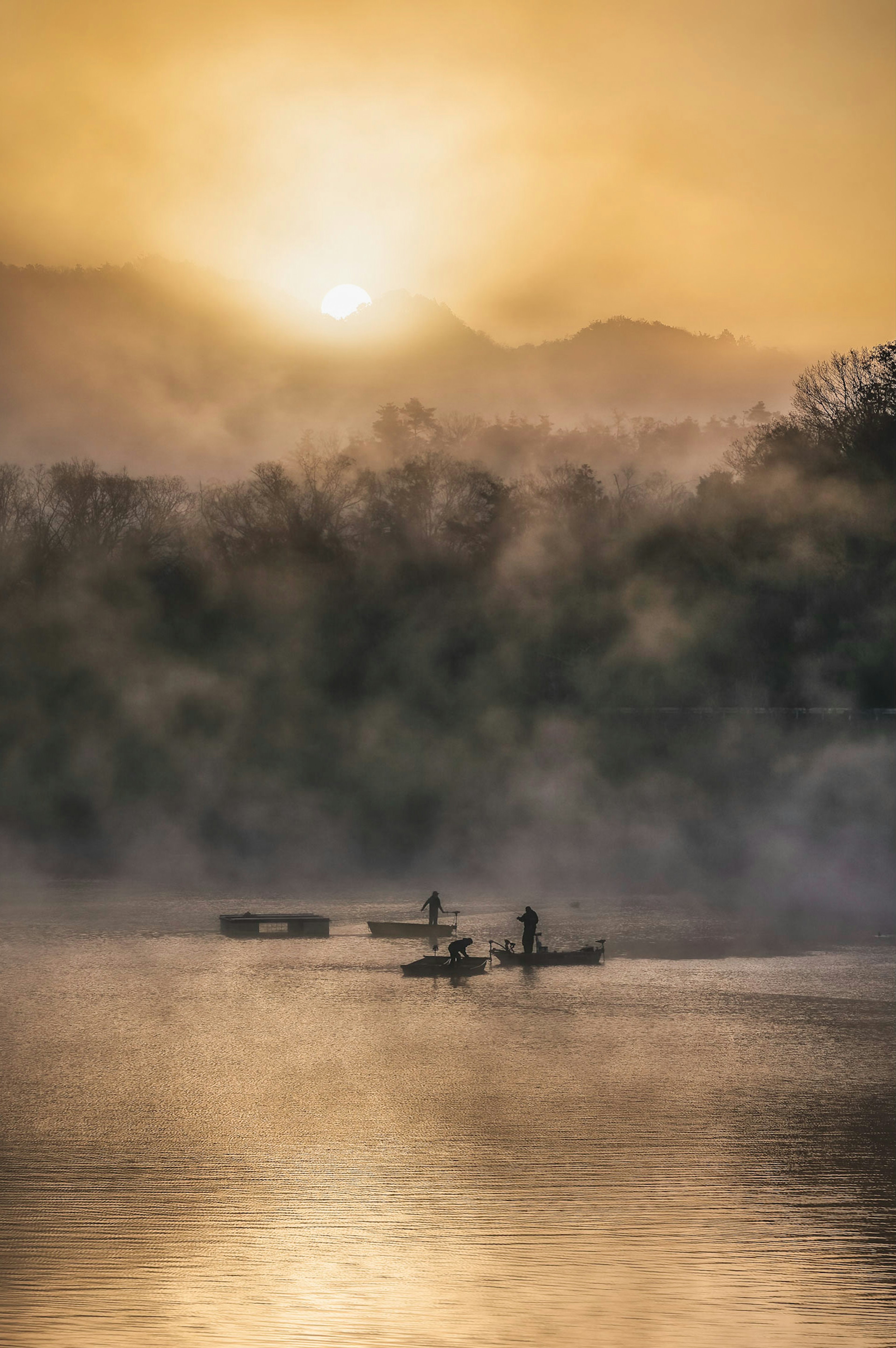 Danau tenang dengan orang-orang mendayung dalam kabut dan matahari terbenam