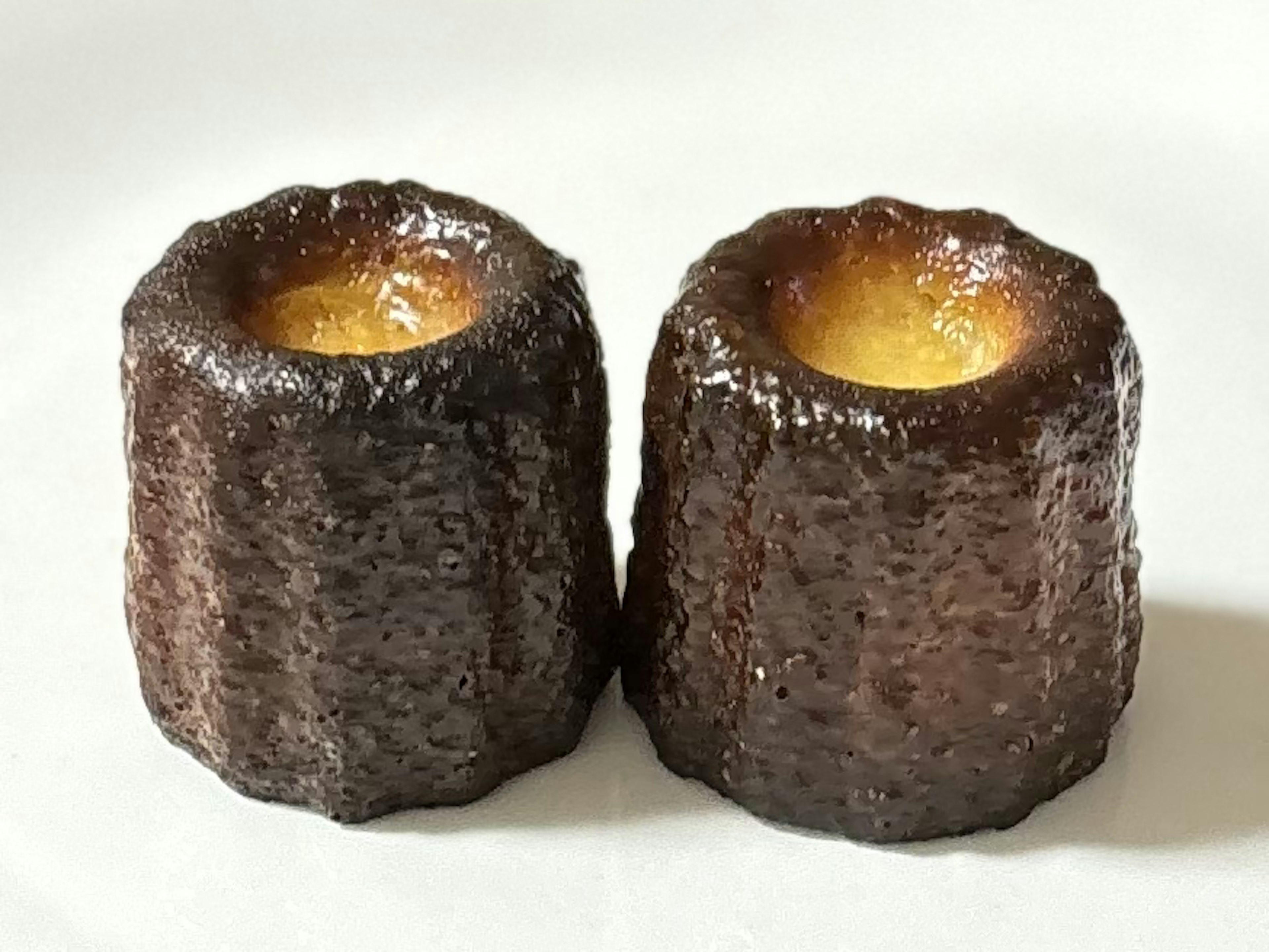 Deux canelés placés sur une assiette blanche