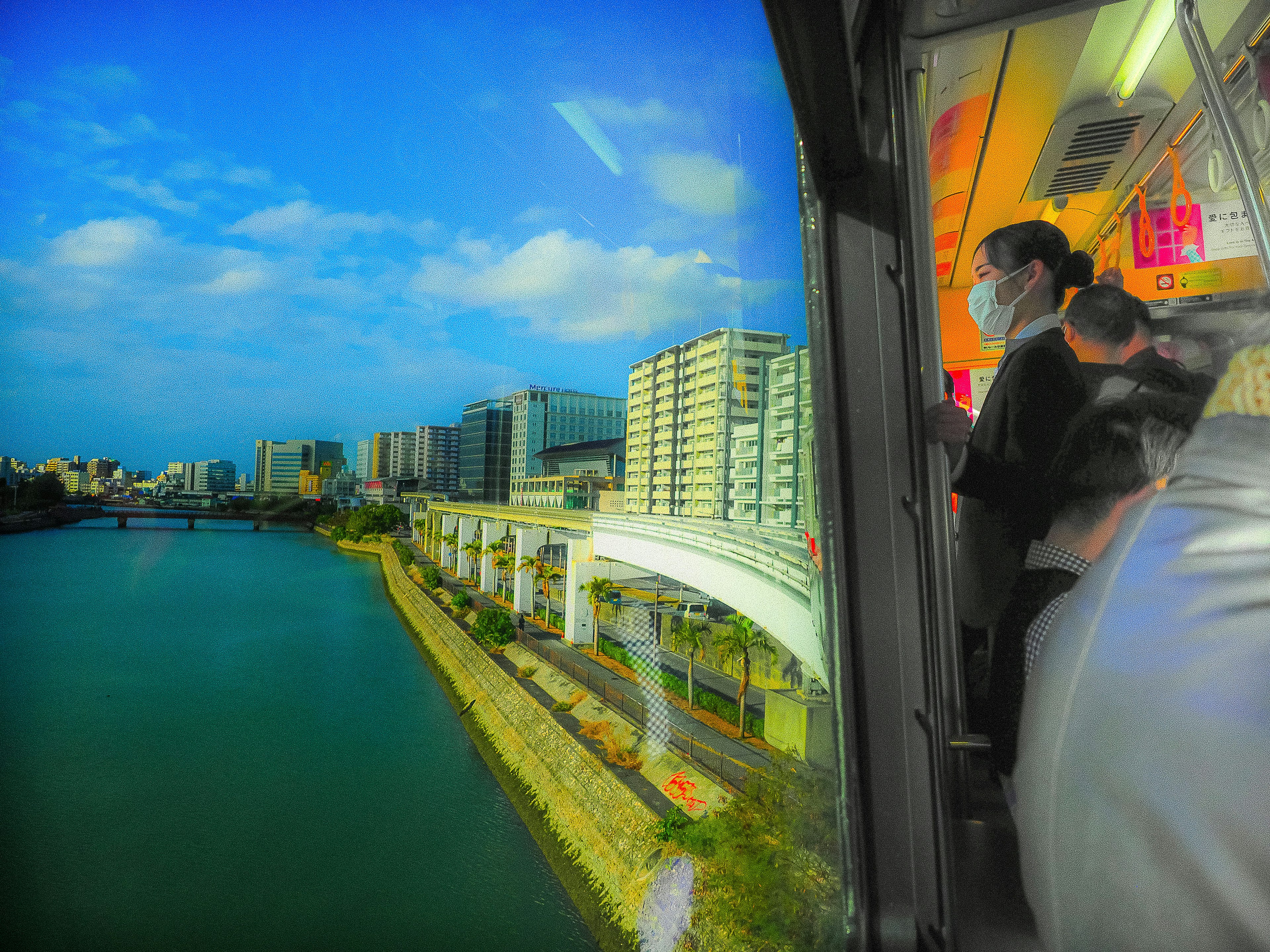 川沿いの都市景観と電車内の乗客が映る風景