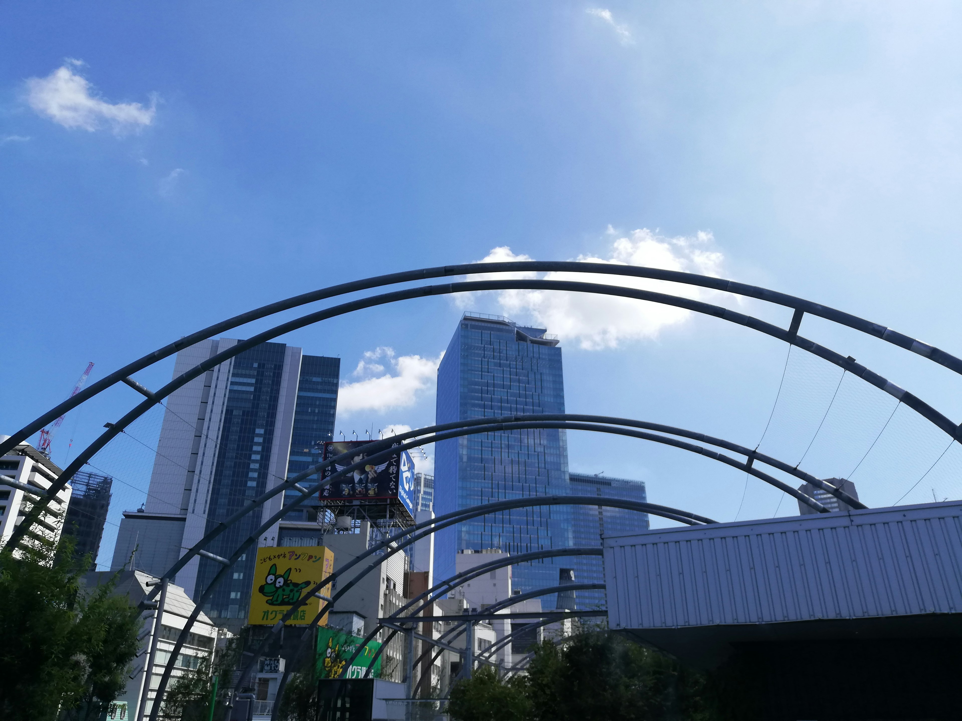 Struktur melengkung dengan gedung pencakar langit dan langit biru di latar belakang