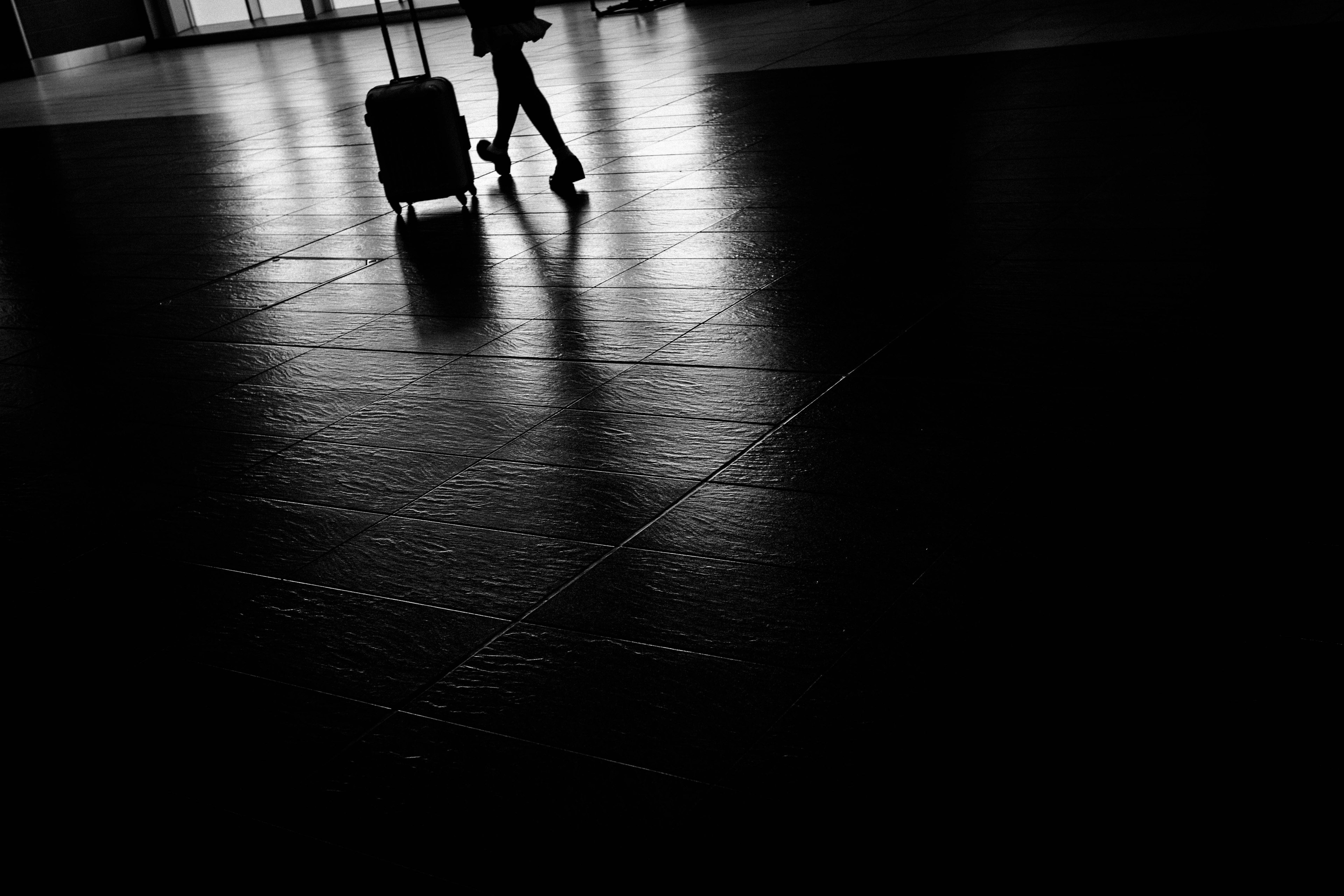 Silhouette of a person walking with luggage in a dark space