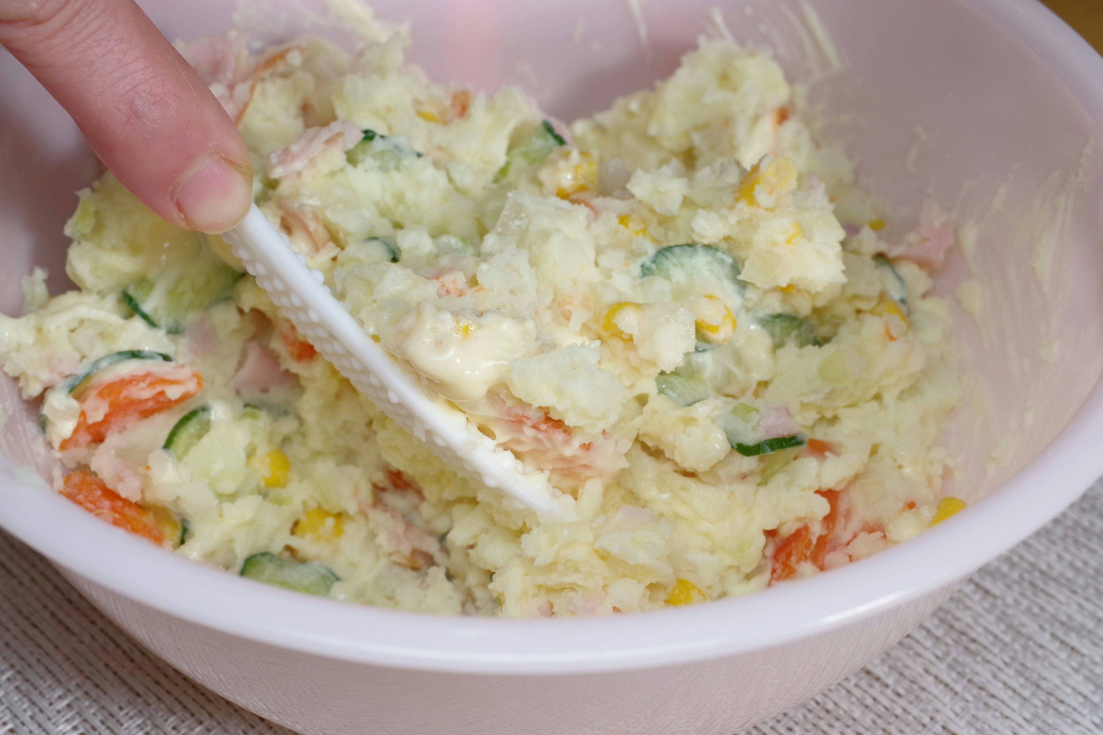 Ingredients being mixed in a bowl of potato salad