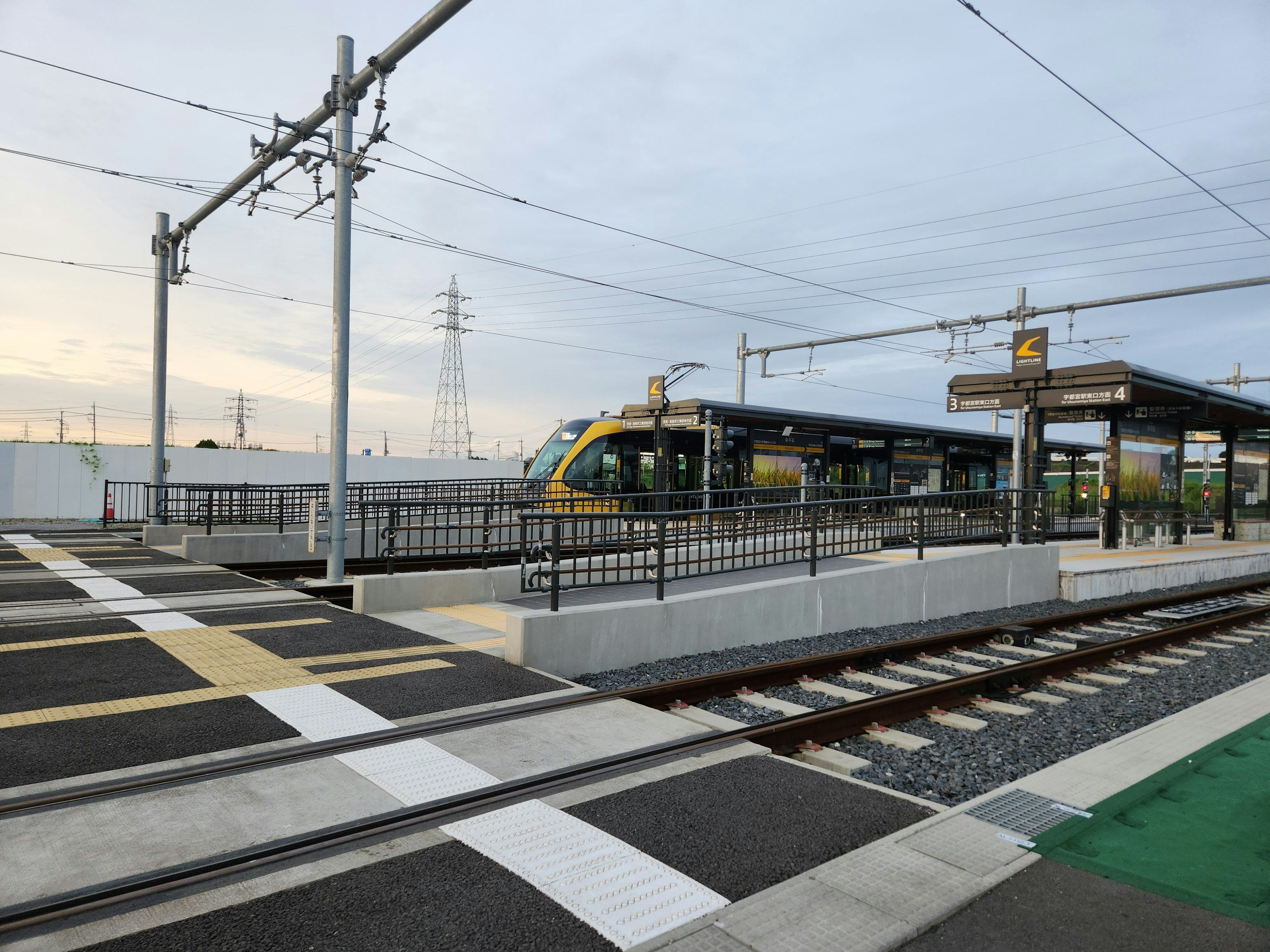 View of a railway station with a green and yellow train stopped at the platform