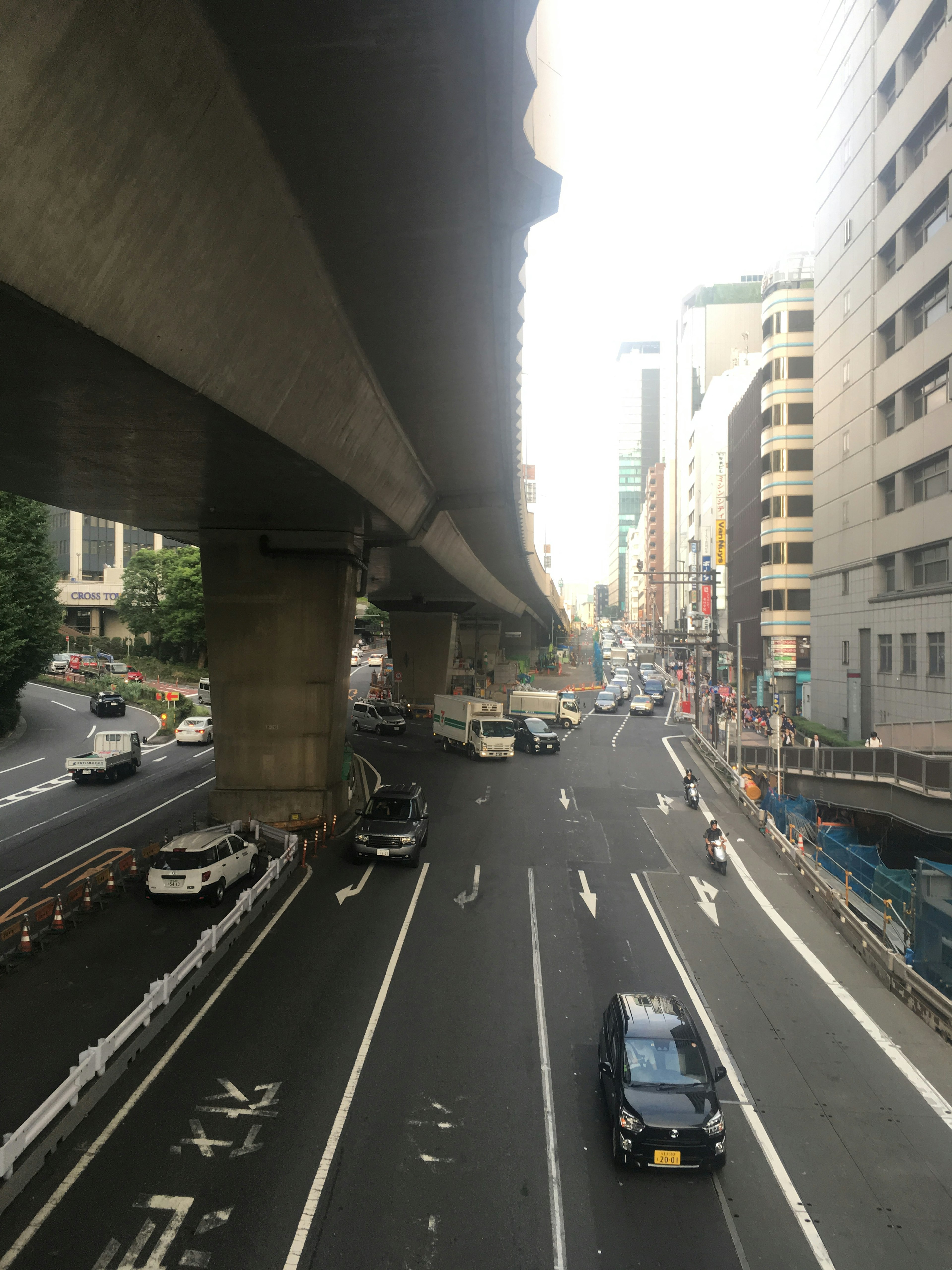 Urban street scene with vehicles beneath an elevated highway