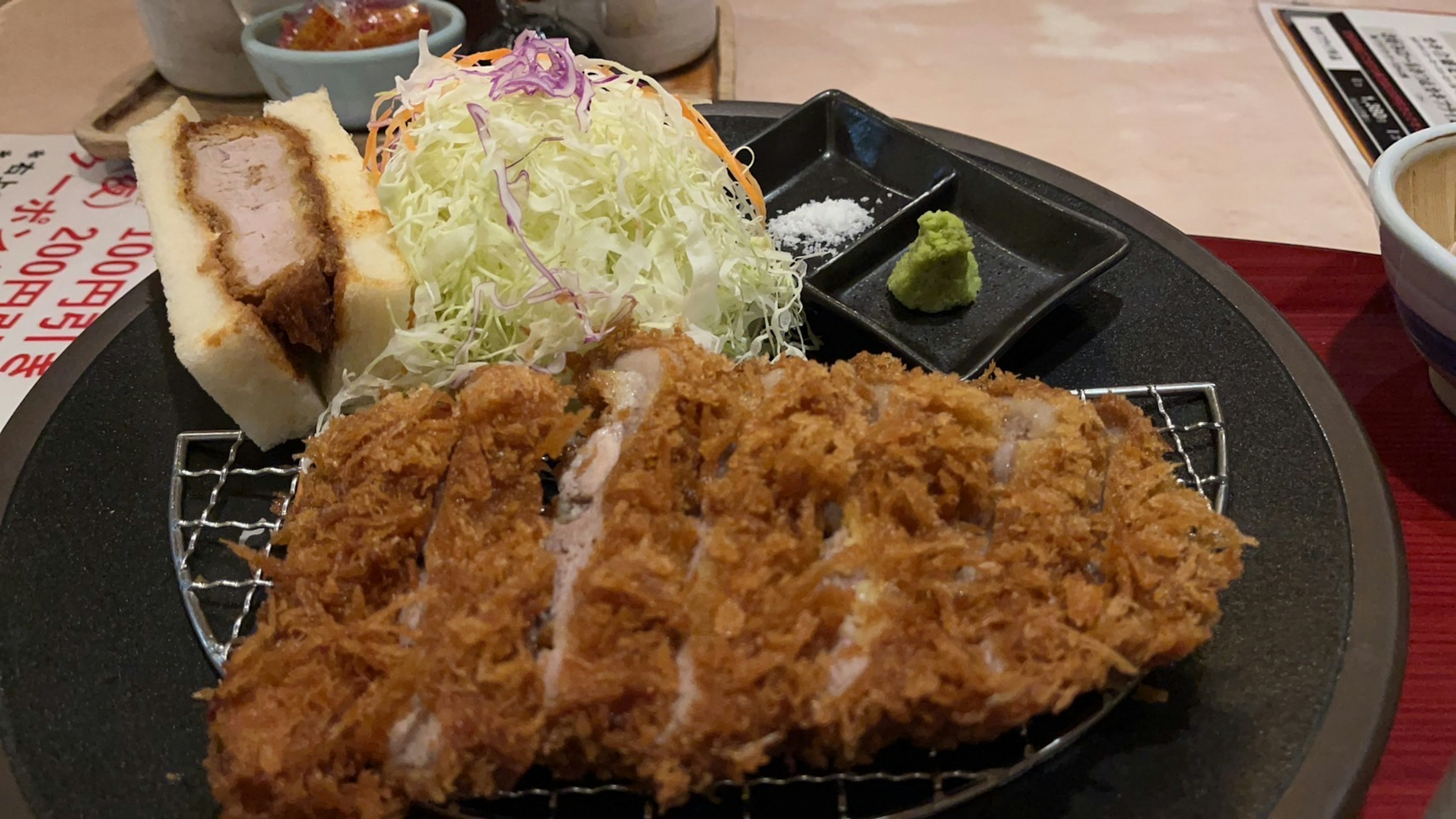 Une assiette avec tonkatsu croustillant, salade de chou et sauces