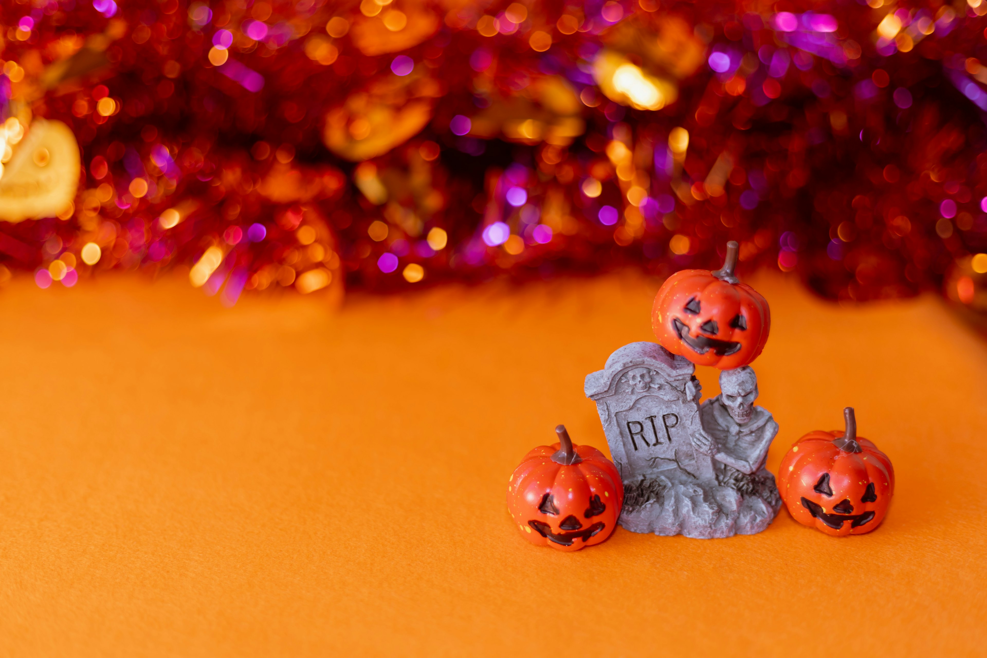 Decorazione di Halloween con una lapide e zucche su uno sfondo arancione