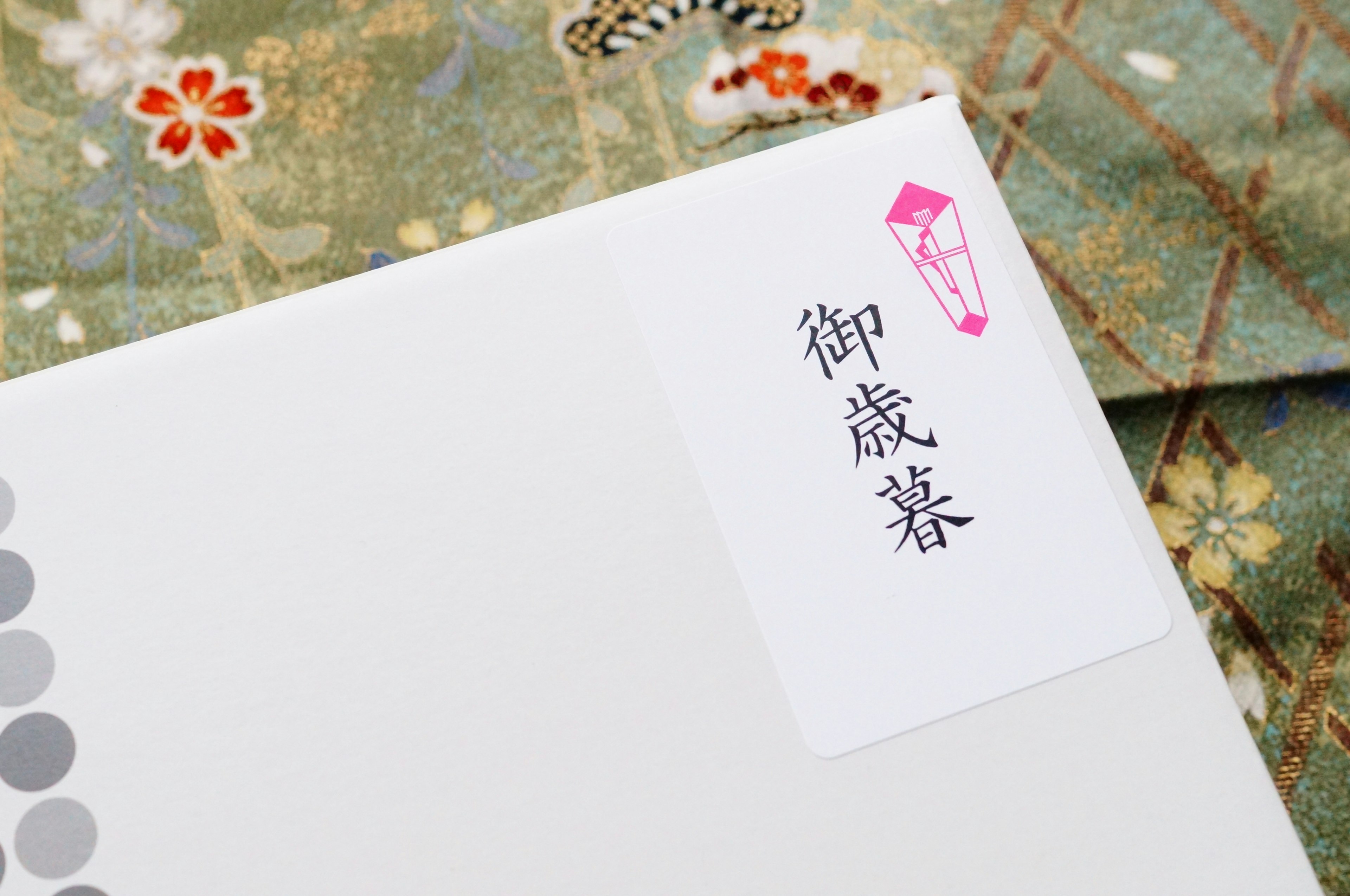 White envelope with a traditional Japanese label and patterned kimono in the background