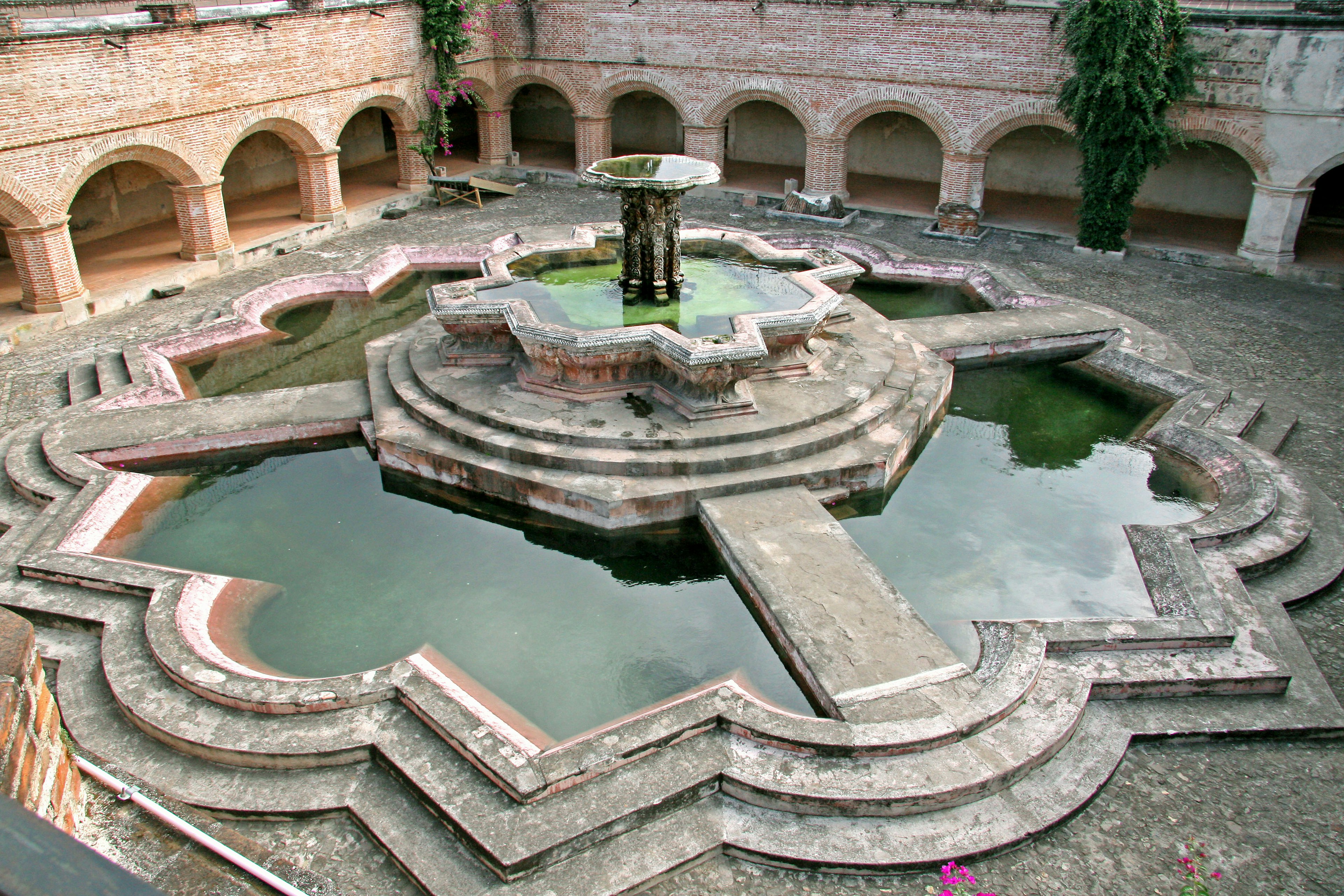 Un cortile panoramico con una bella fontana in pietra e bordi geometrici intricati con acqua verde calma