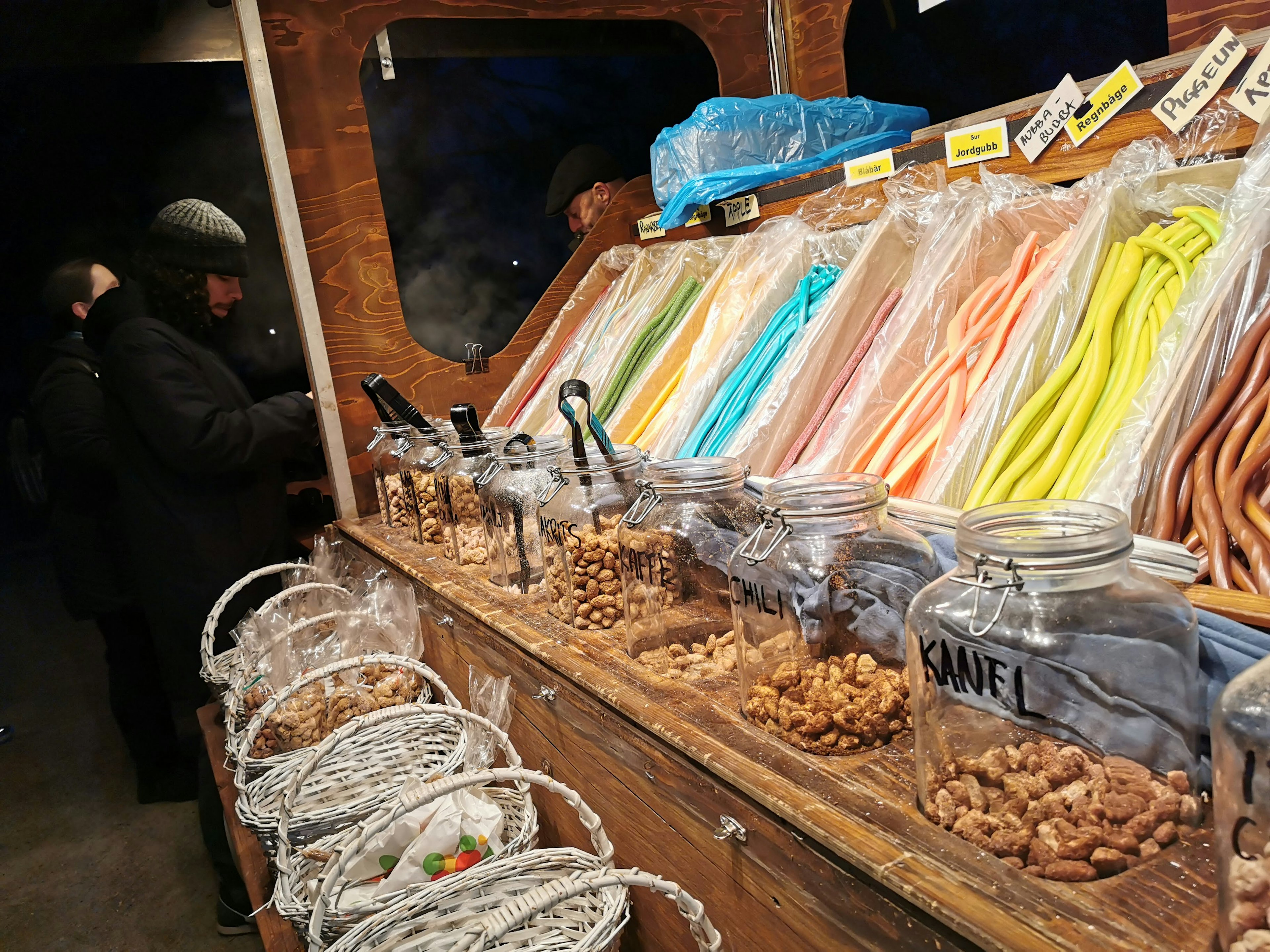 Caramelle colorate e noci esposte in un banco dolci