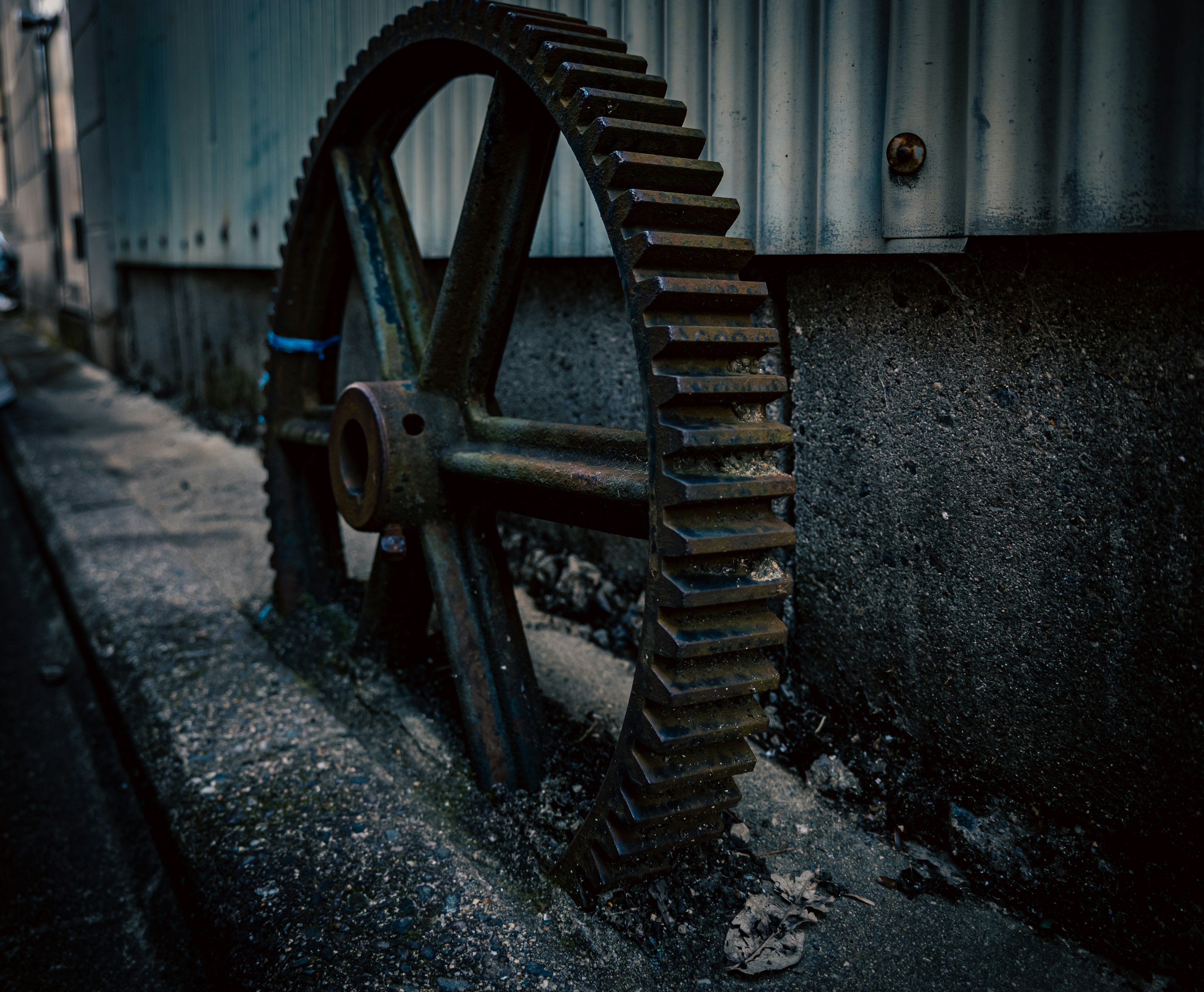 Rusty gear wheel leaning against a wall