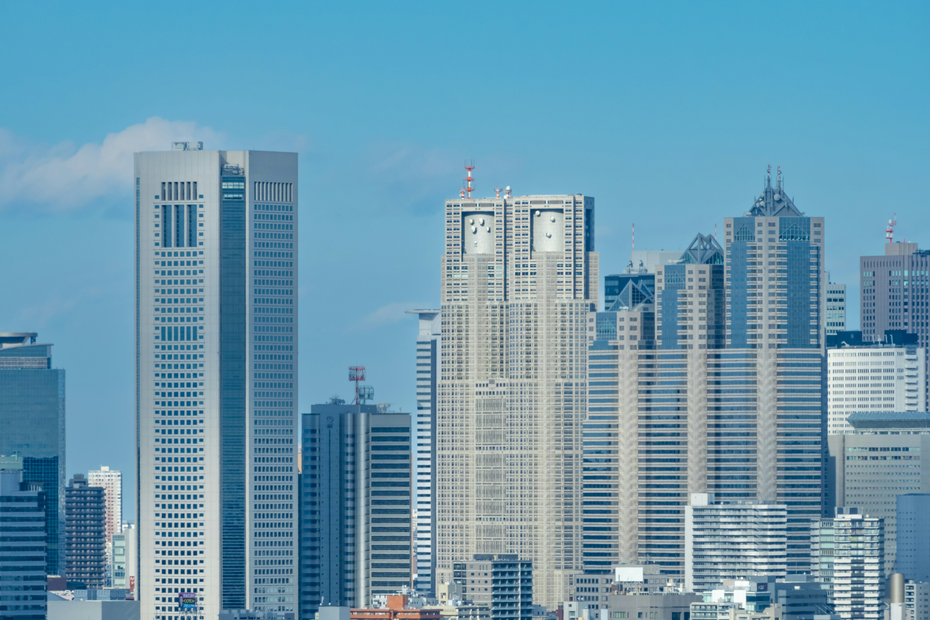 Gedung Pemerintahan Metropolitan Tokyo dan gedung pencakar langit di bawah langit biru