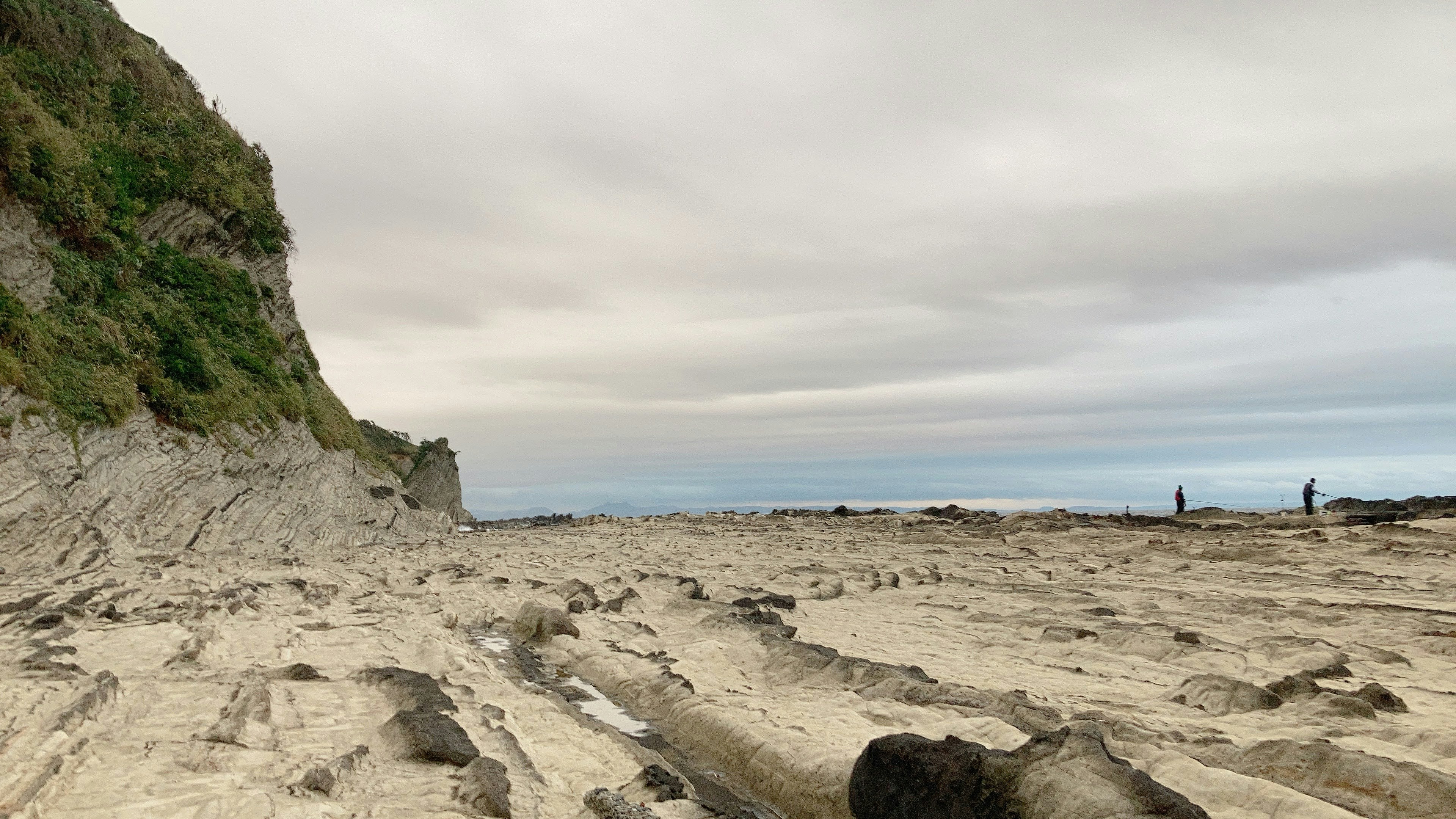 Coastal landscape with rocky shore and distant figures walking