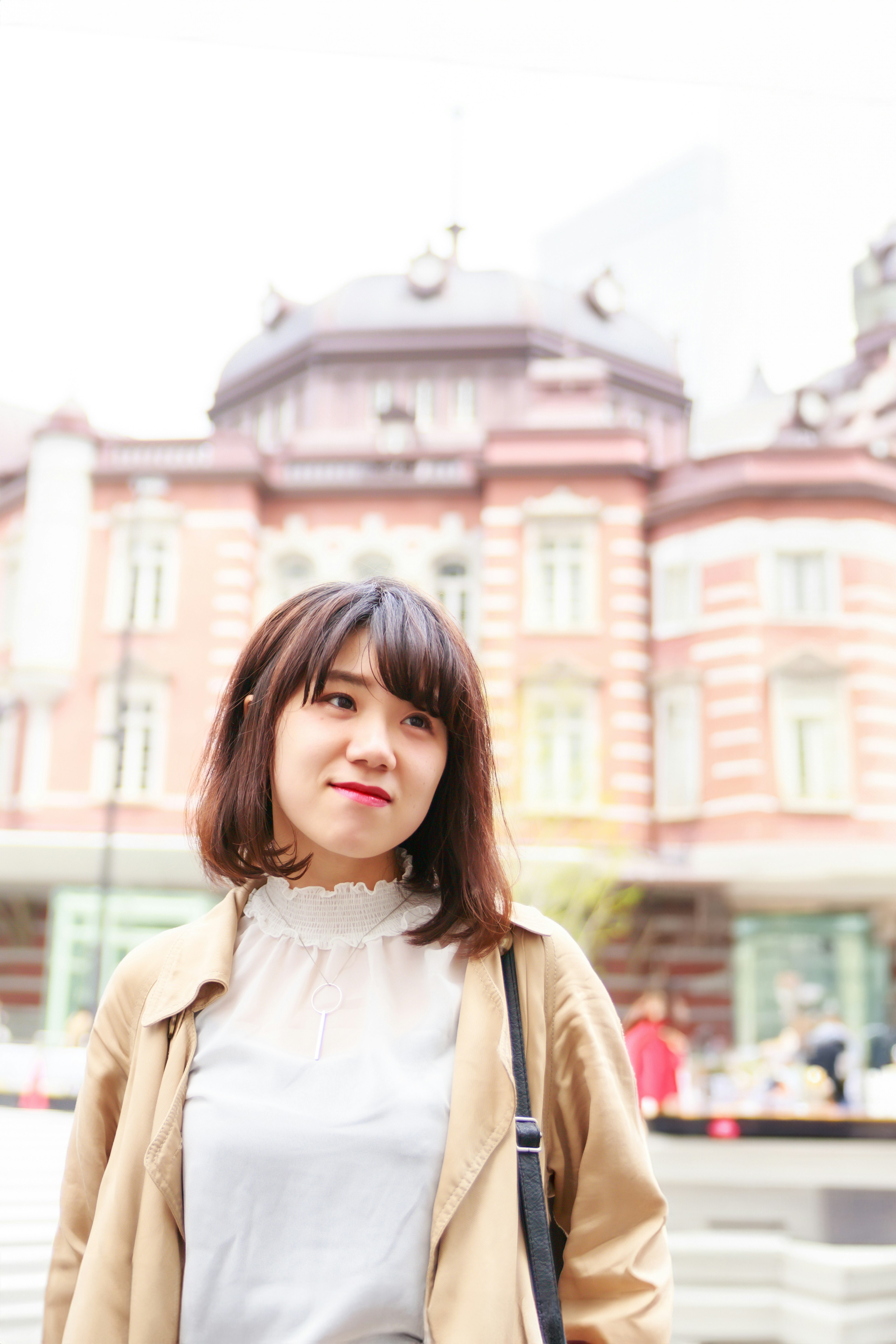 Wanita muda tersenyum di depan Stasiun Tokyo