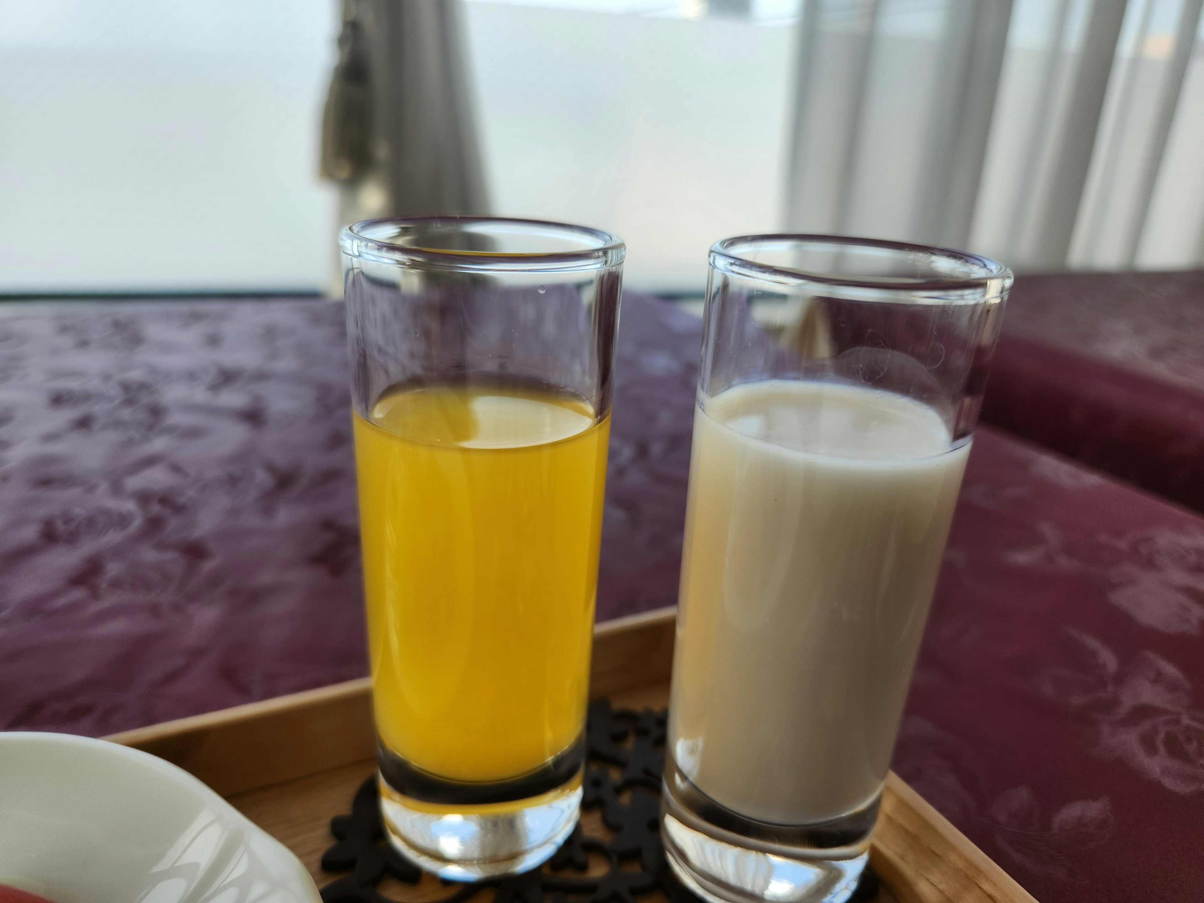 Two shot glasses containing yellow juice and white beverage