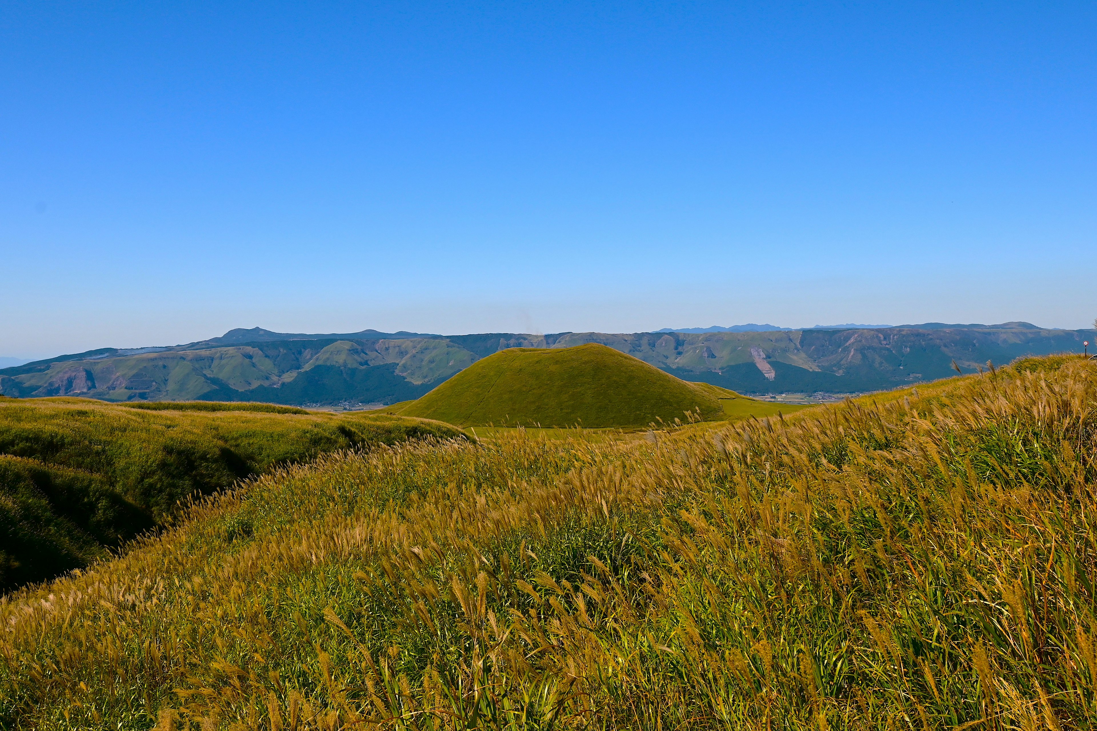 青空の下で草原に囲まれた緑の丘の風景