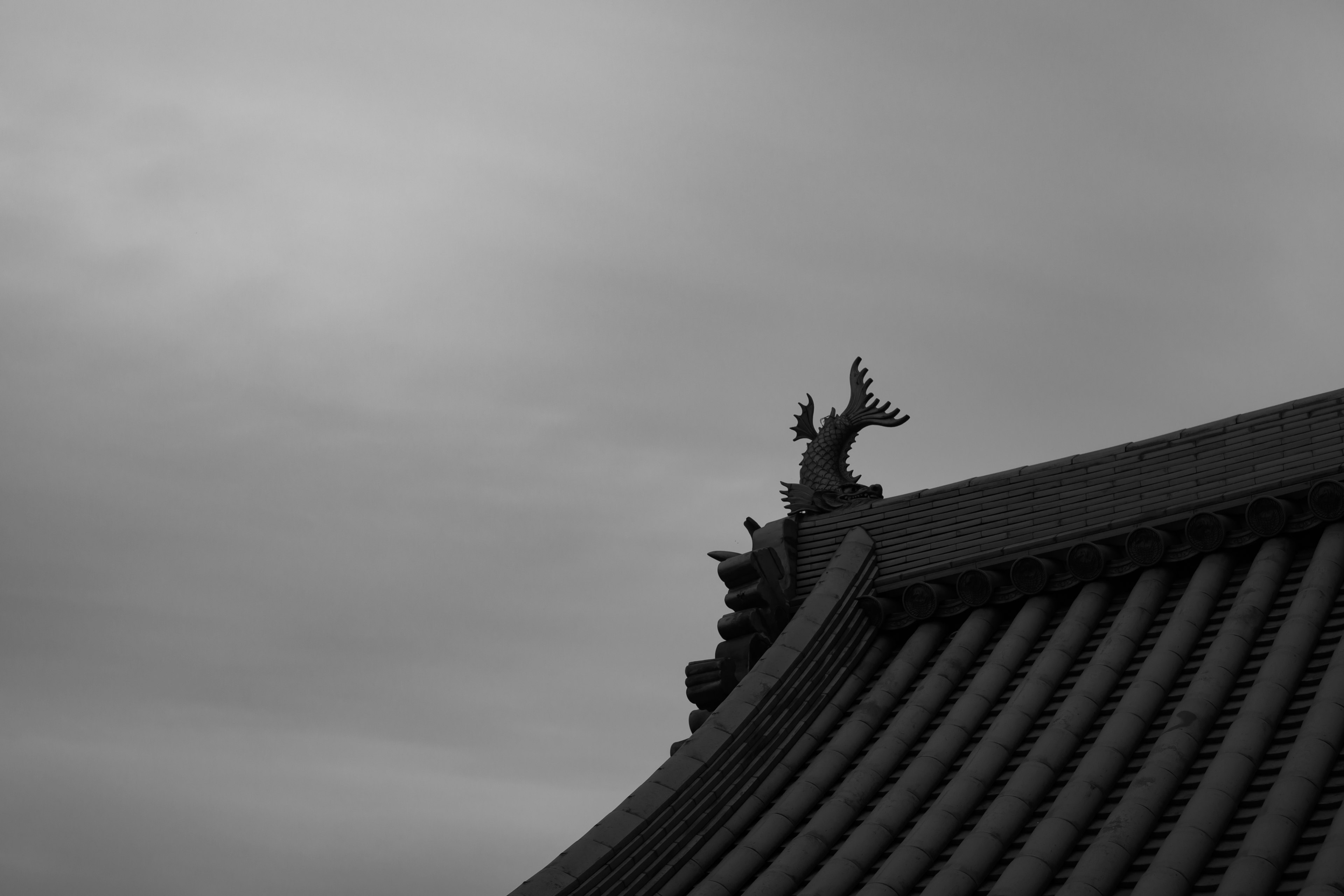 屋根の上にある装飾的なドラゴンの彫刻と雲のある空