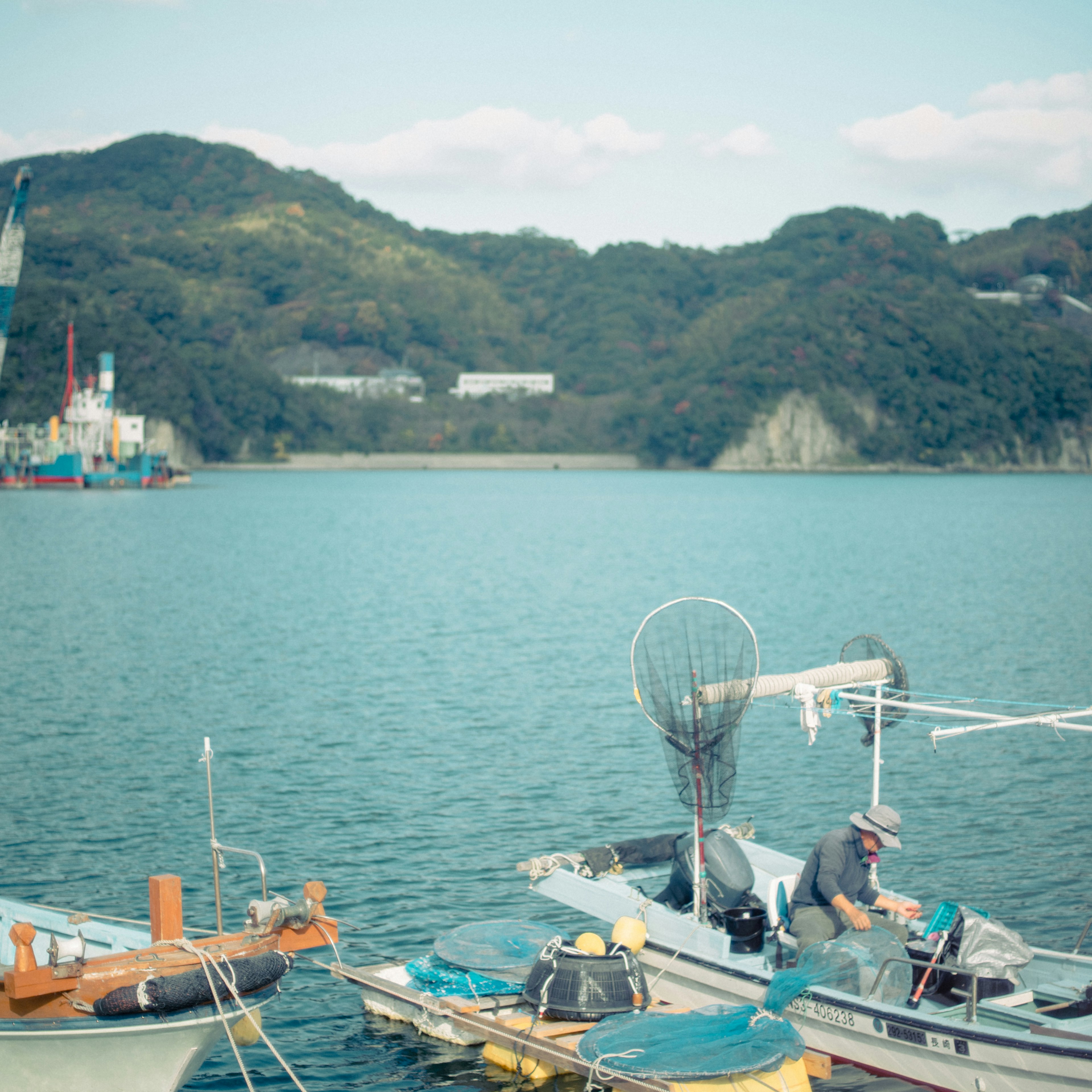 静かな海の景色に浮かぶ漁船と背景の山々