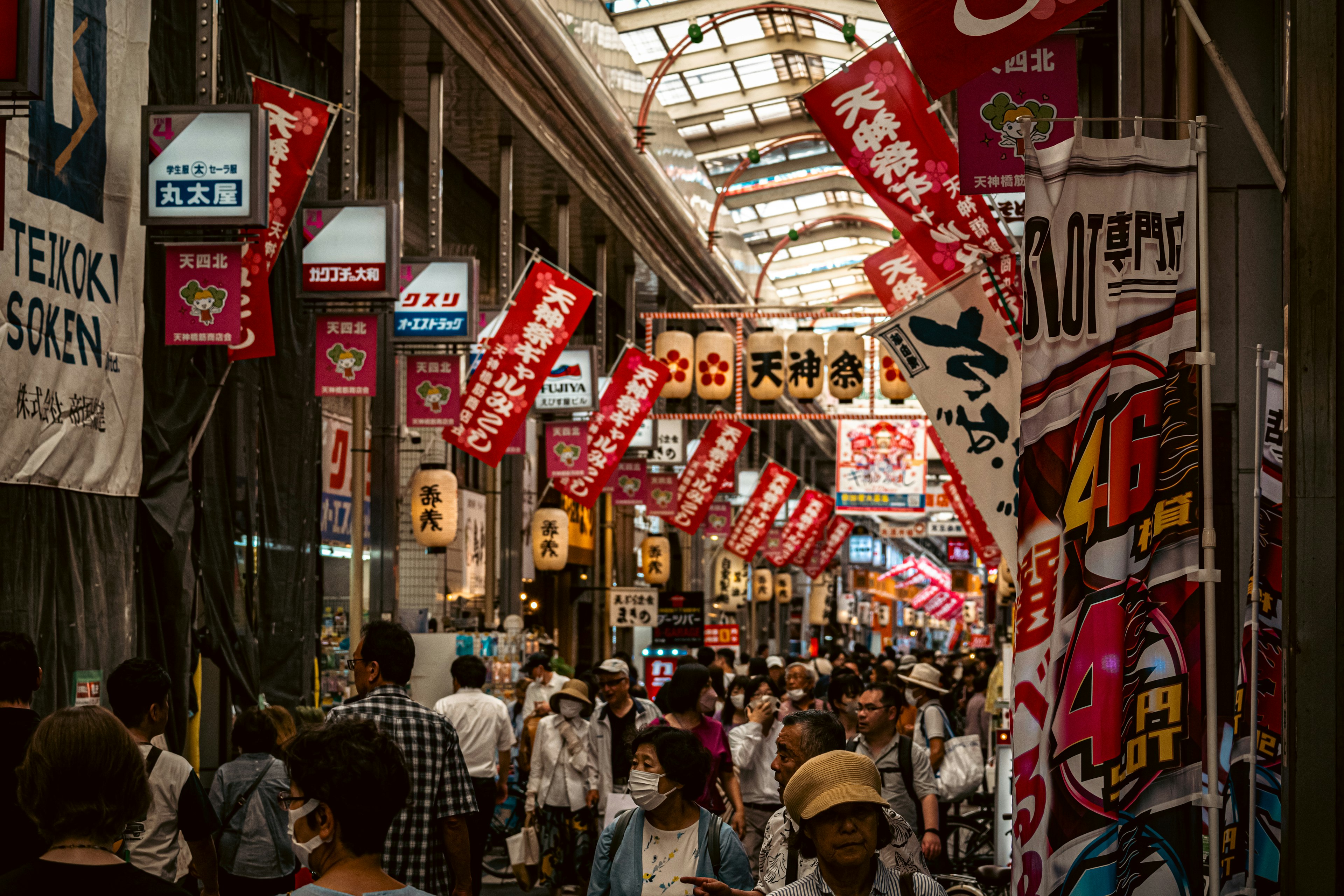 Calle comercial concurrida llena de personas y pancartas rojas prominentes