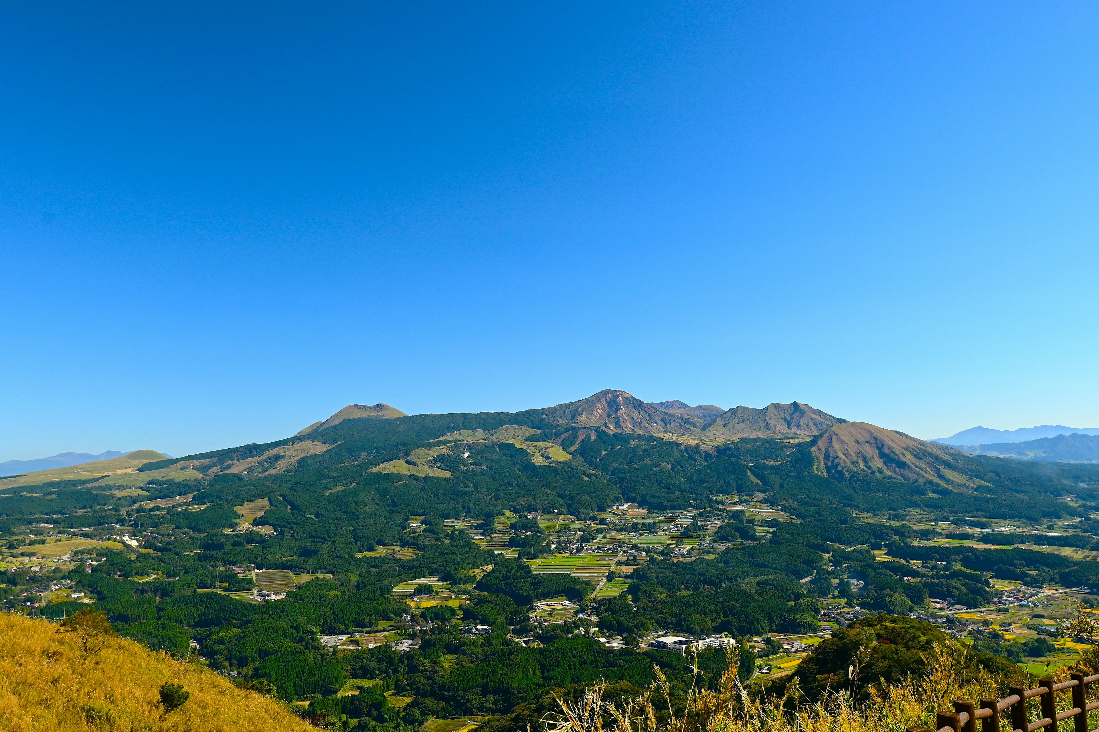 晴朗蓝天下绿色山丘和山脉的全景