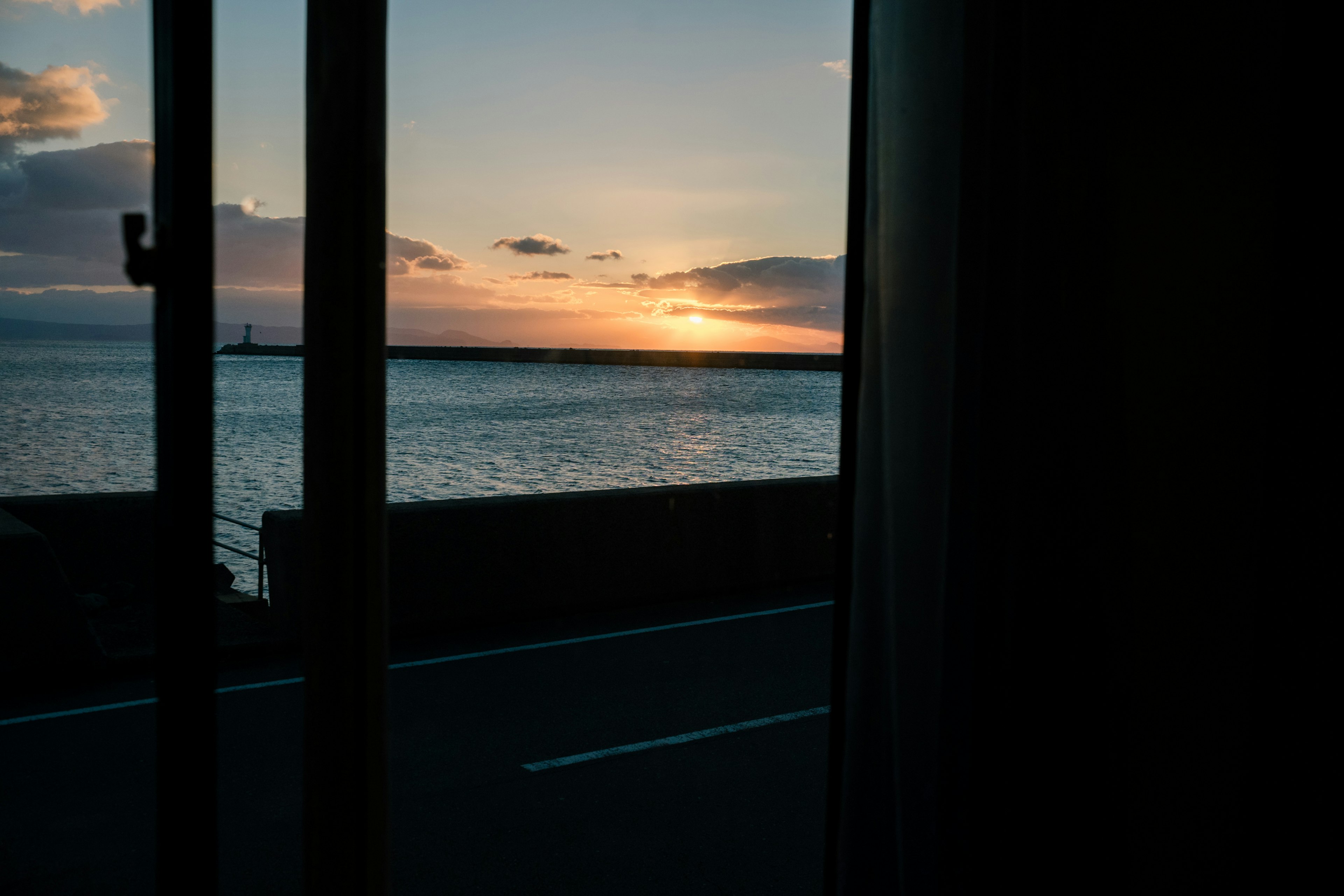 窓越しに見える海と夕日の景色