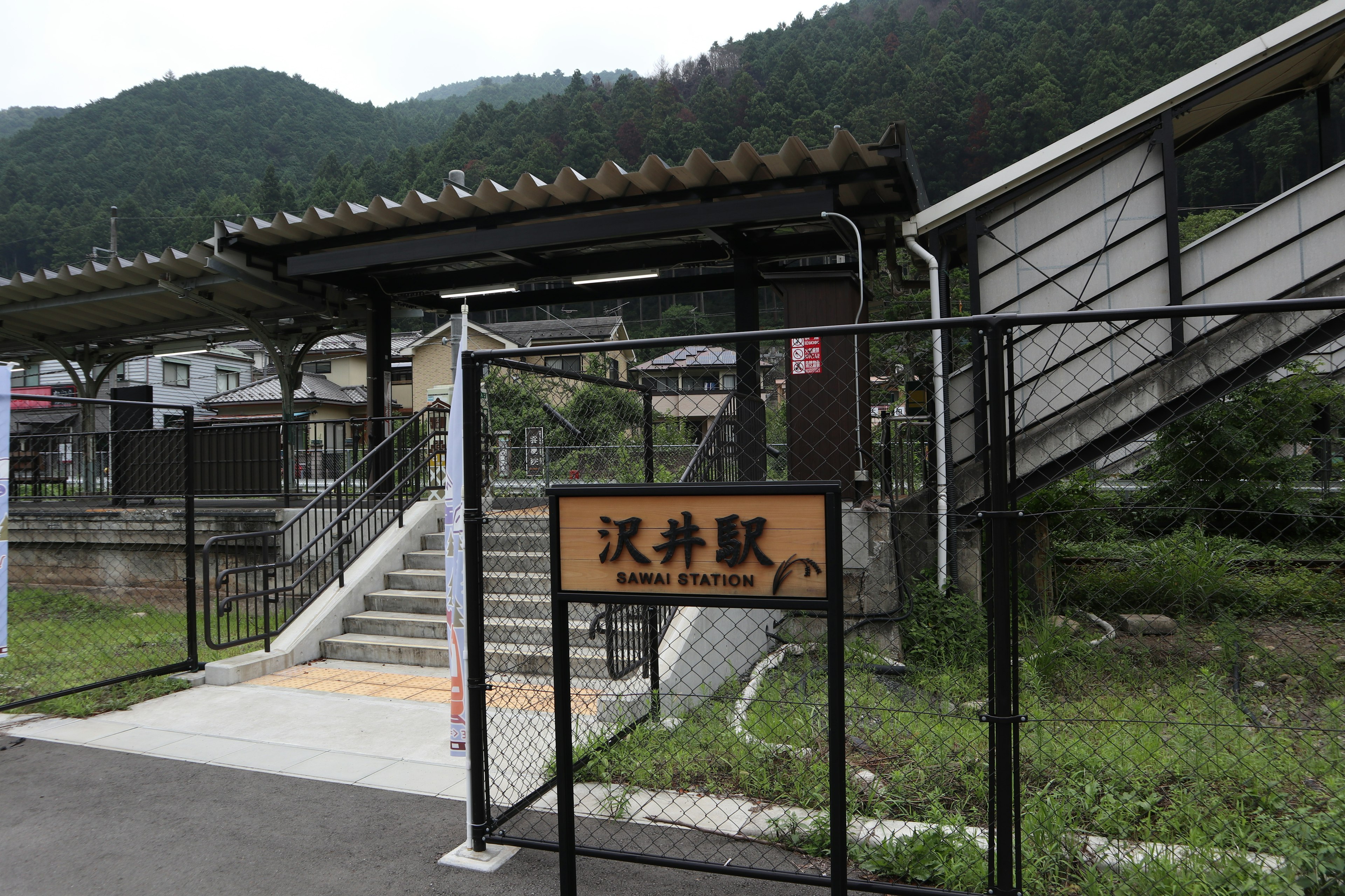 山の中にある静かな駅の外観で、階段とサインが見える