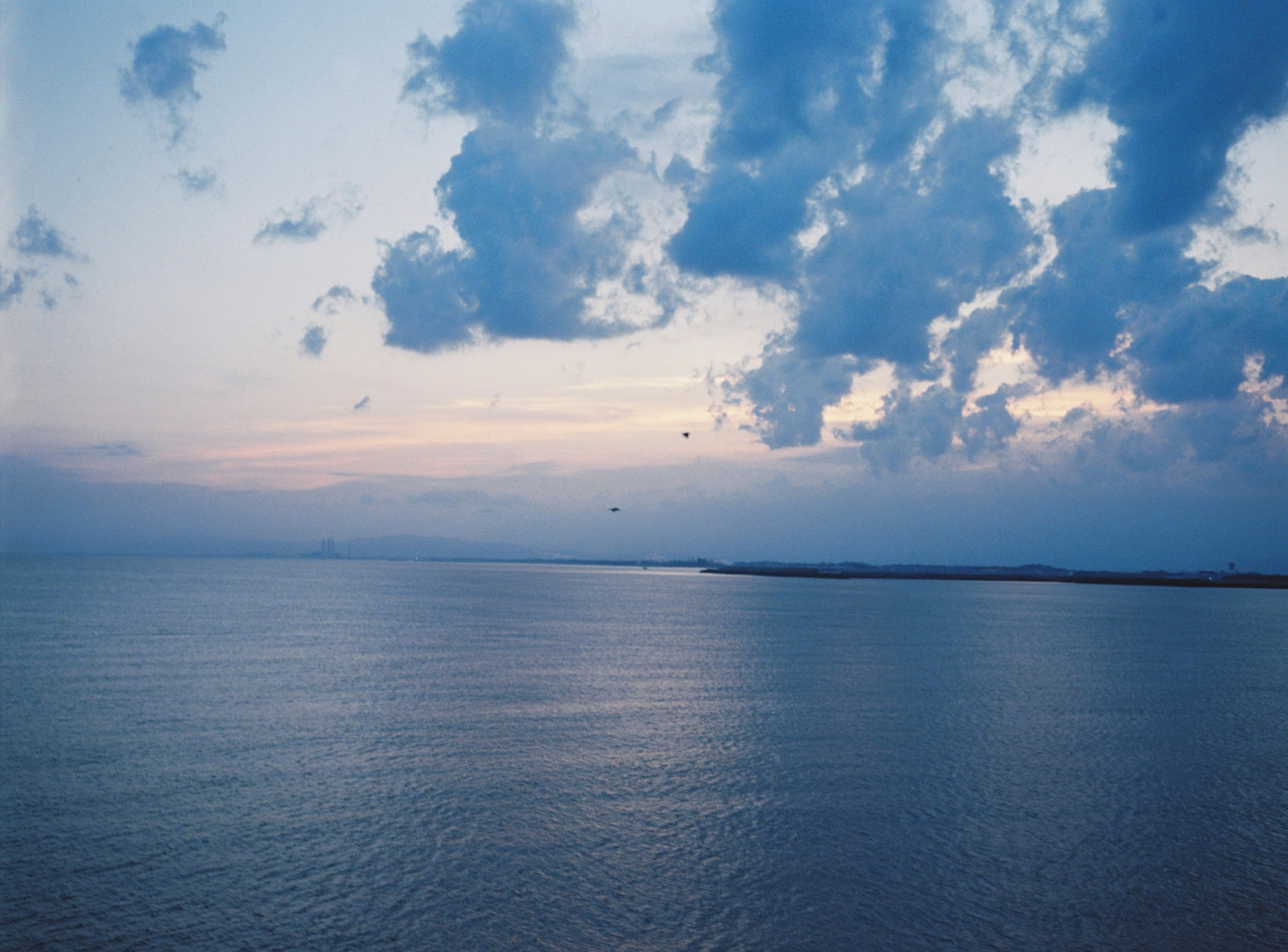 Serene seascape at dusk with blue waters and scattered clouds