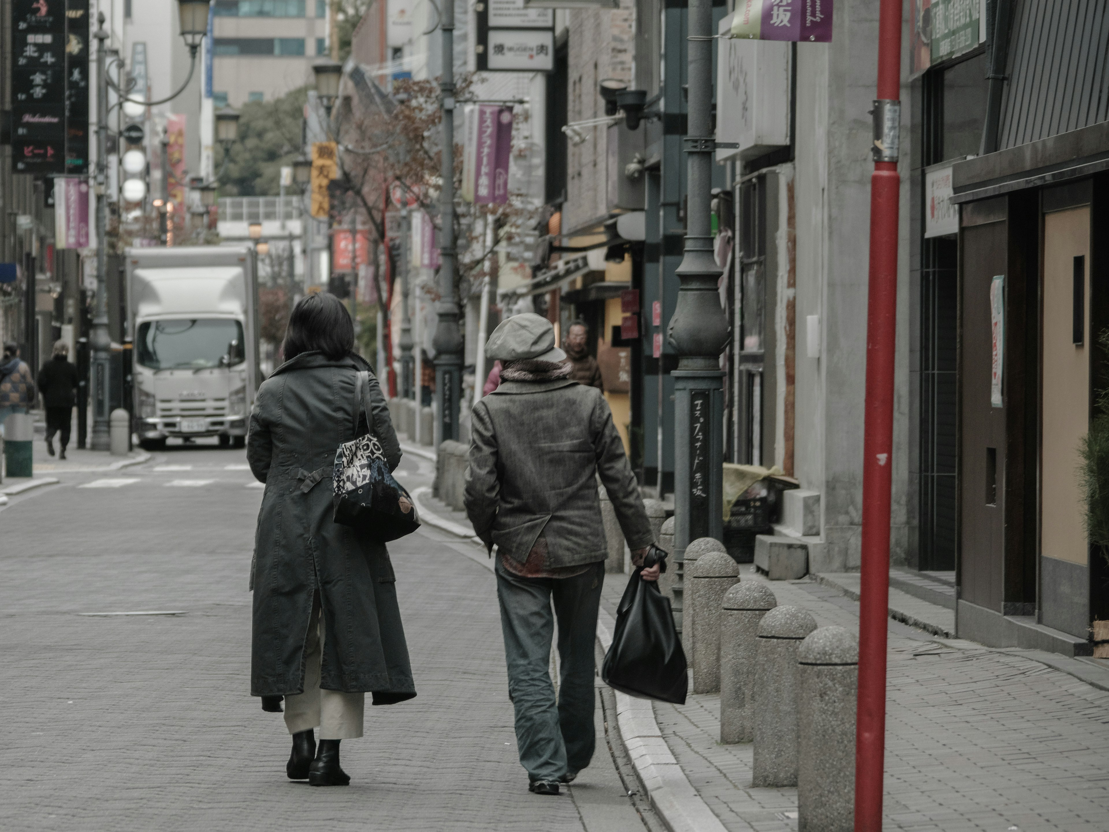 Zwei Frauen gehen in einer Stadtstraße, die von Geschäften und Gebäuden gesäumt ist