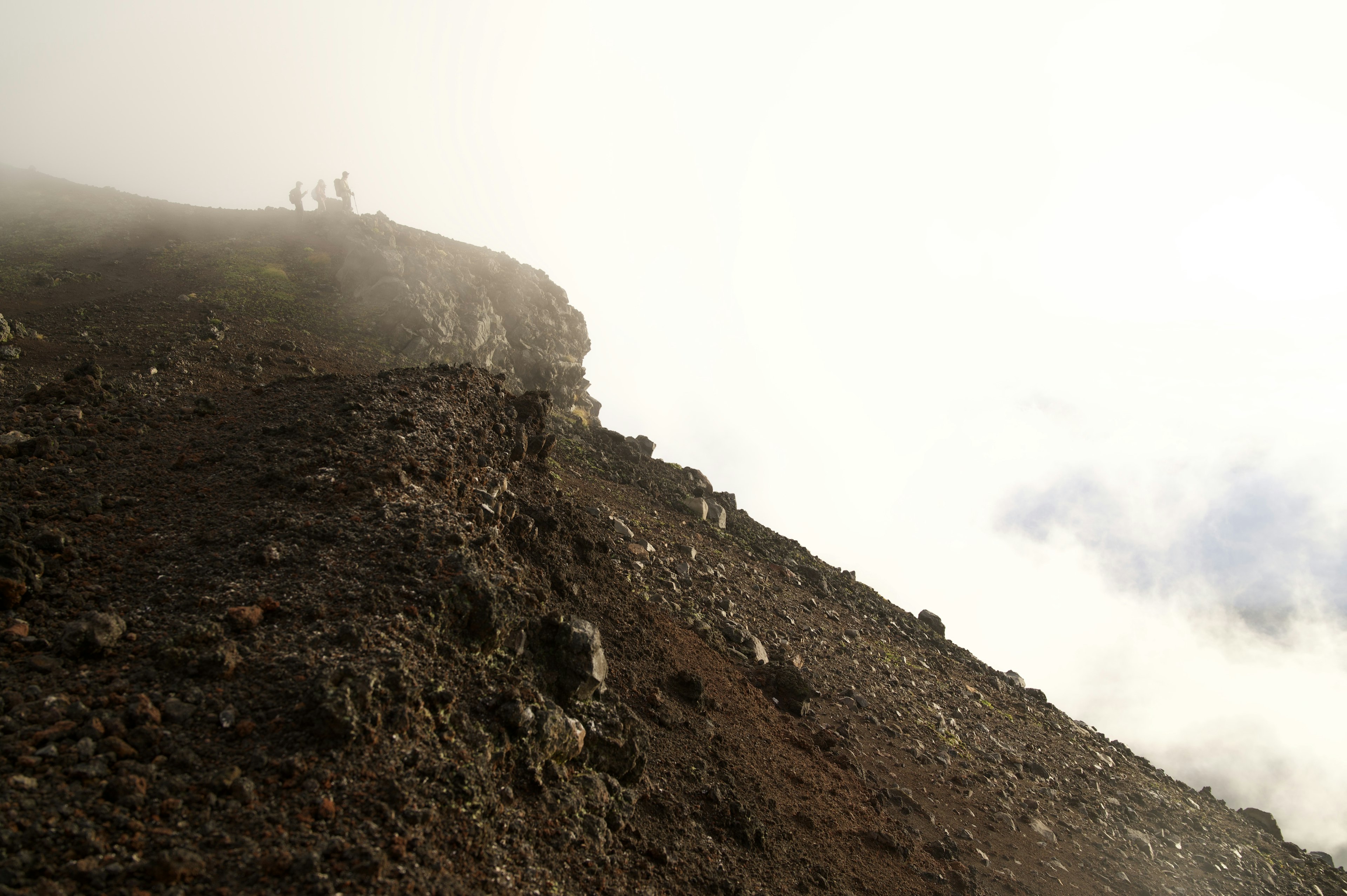 霧に包まれた山の斜面と登山者のシルエット