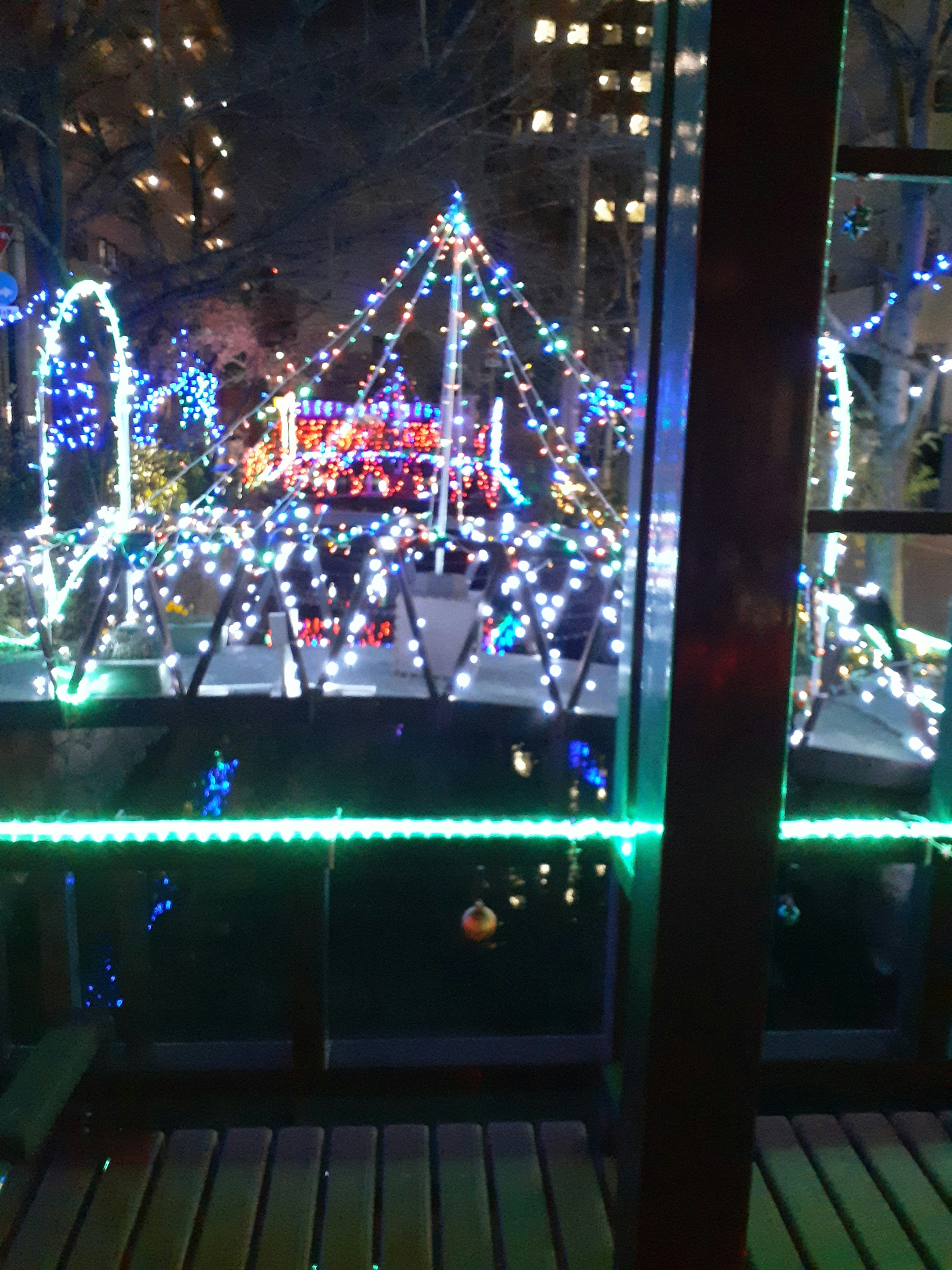 Scène nocturne avec des lumières colorées illuminant un parc décoré de manière festive