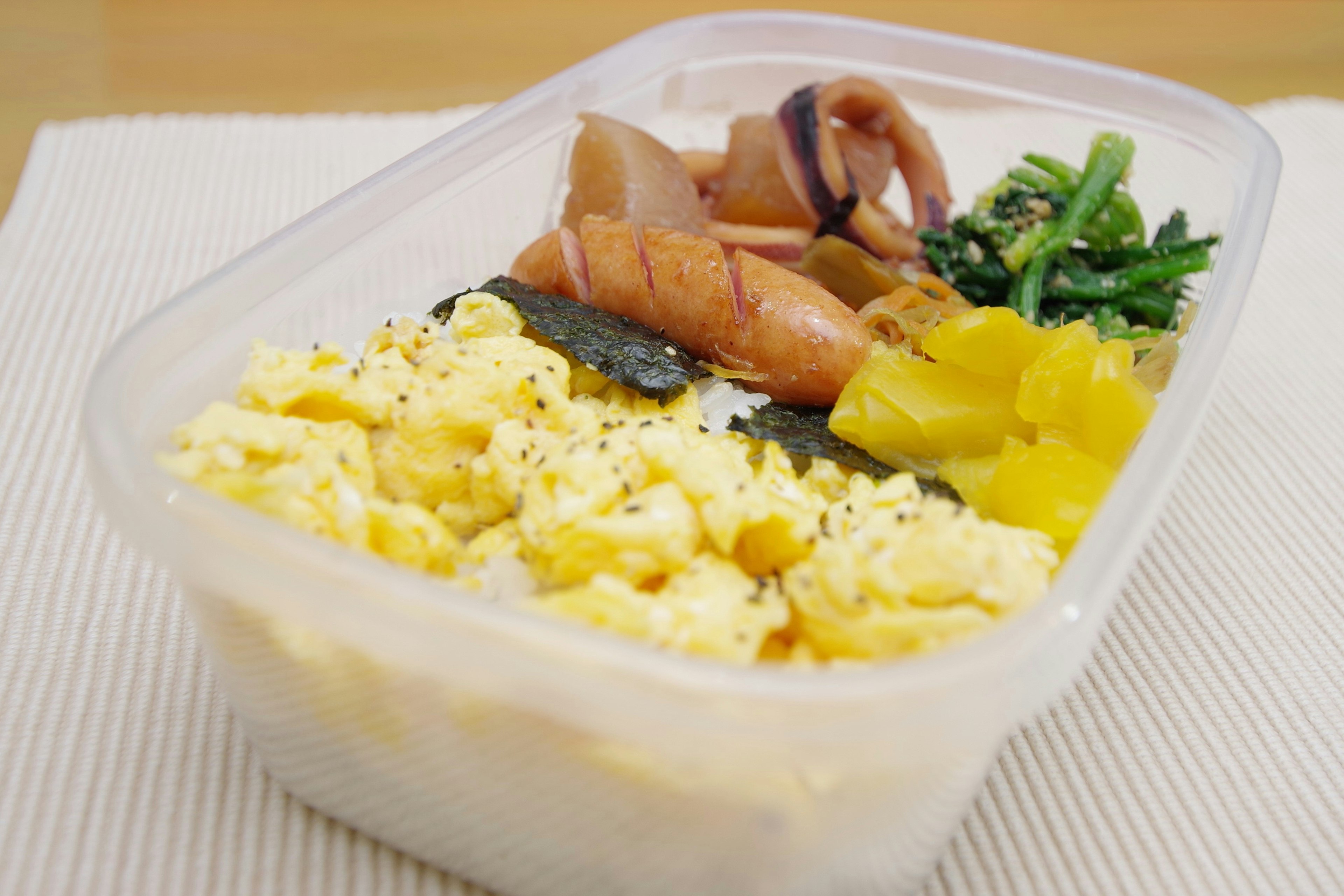 Bento box with scrambled eggs seaweed rice and colorful vegetables