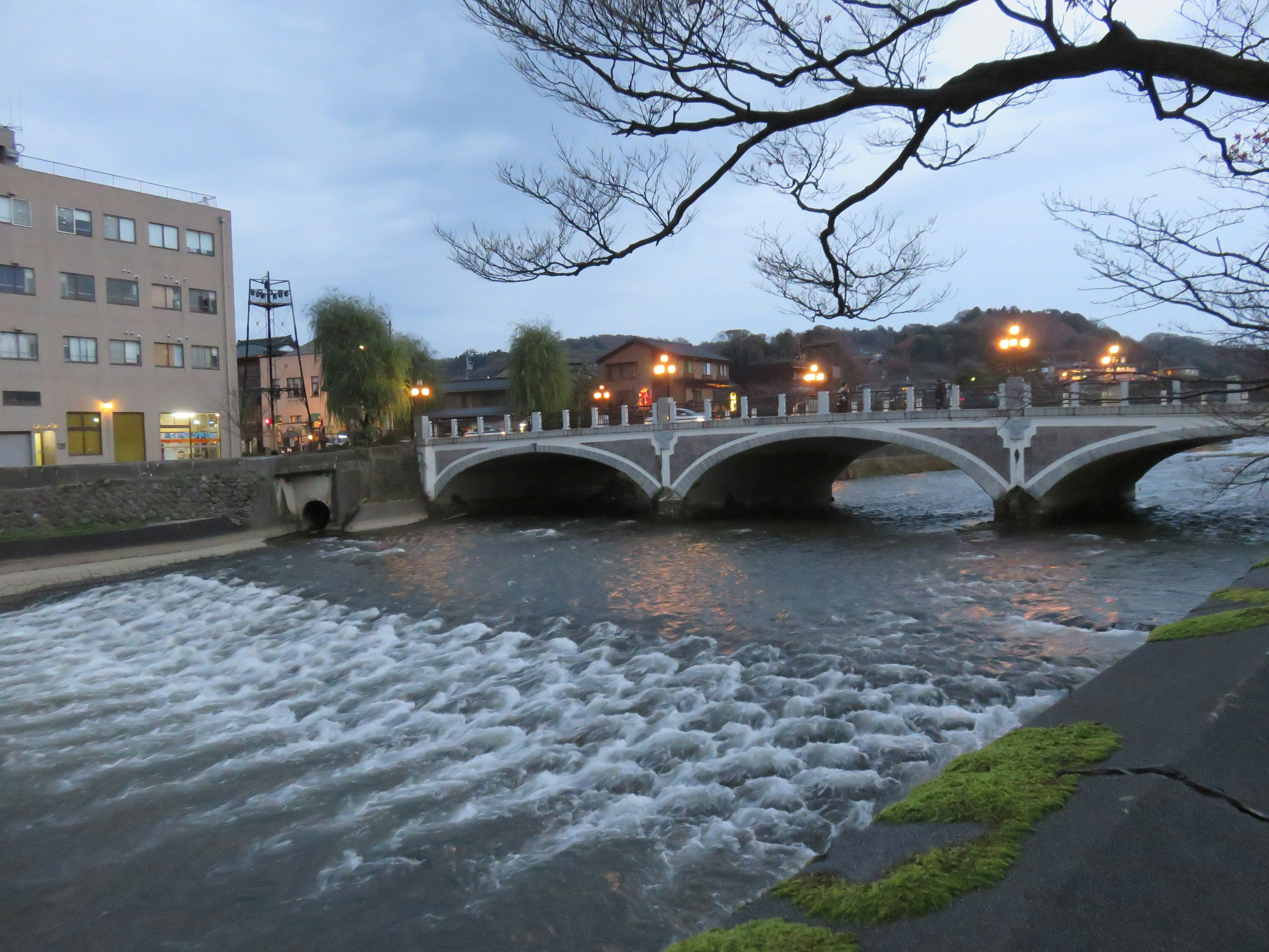 Vista notturna di un ponte su un fiume con acqua che scorre