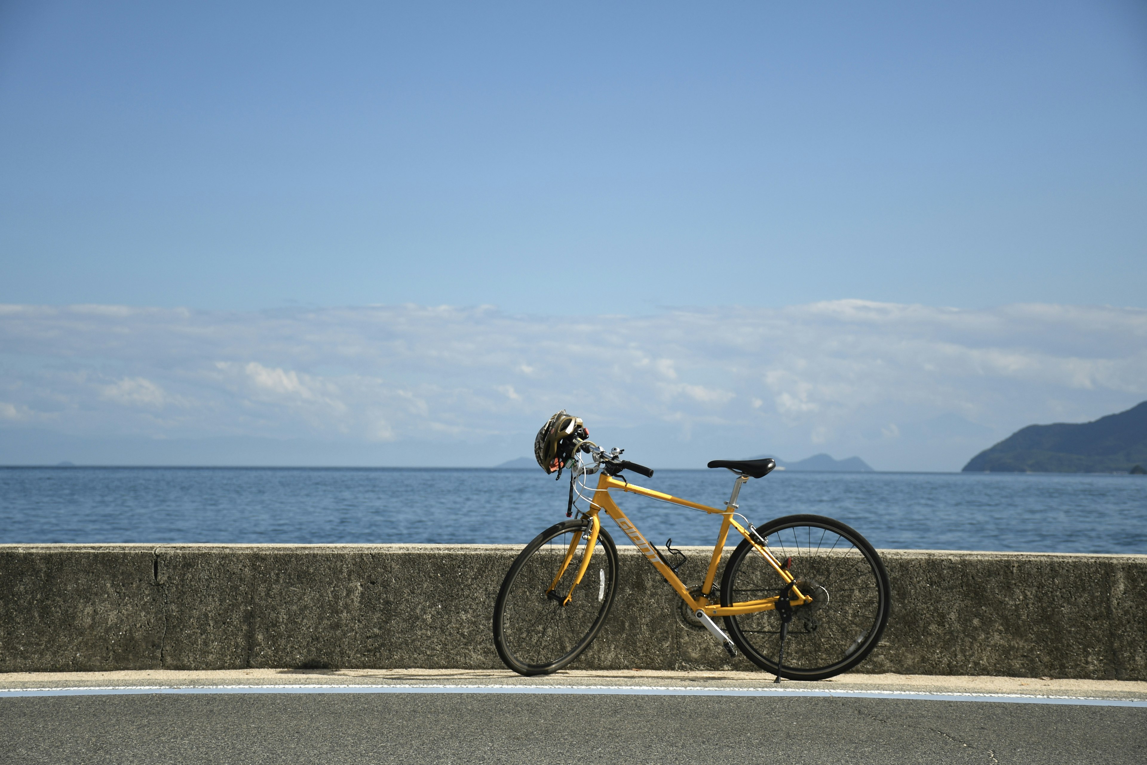 Una bicicleta amarilla estacionada cerca del océano bajo un cielo azul claro