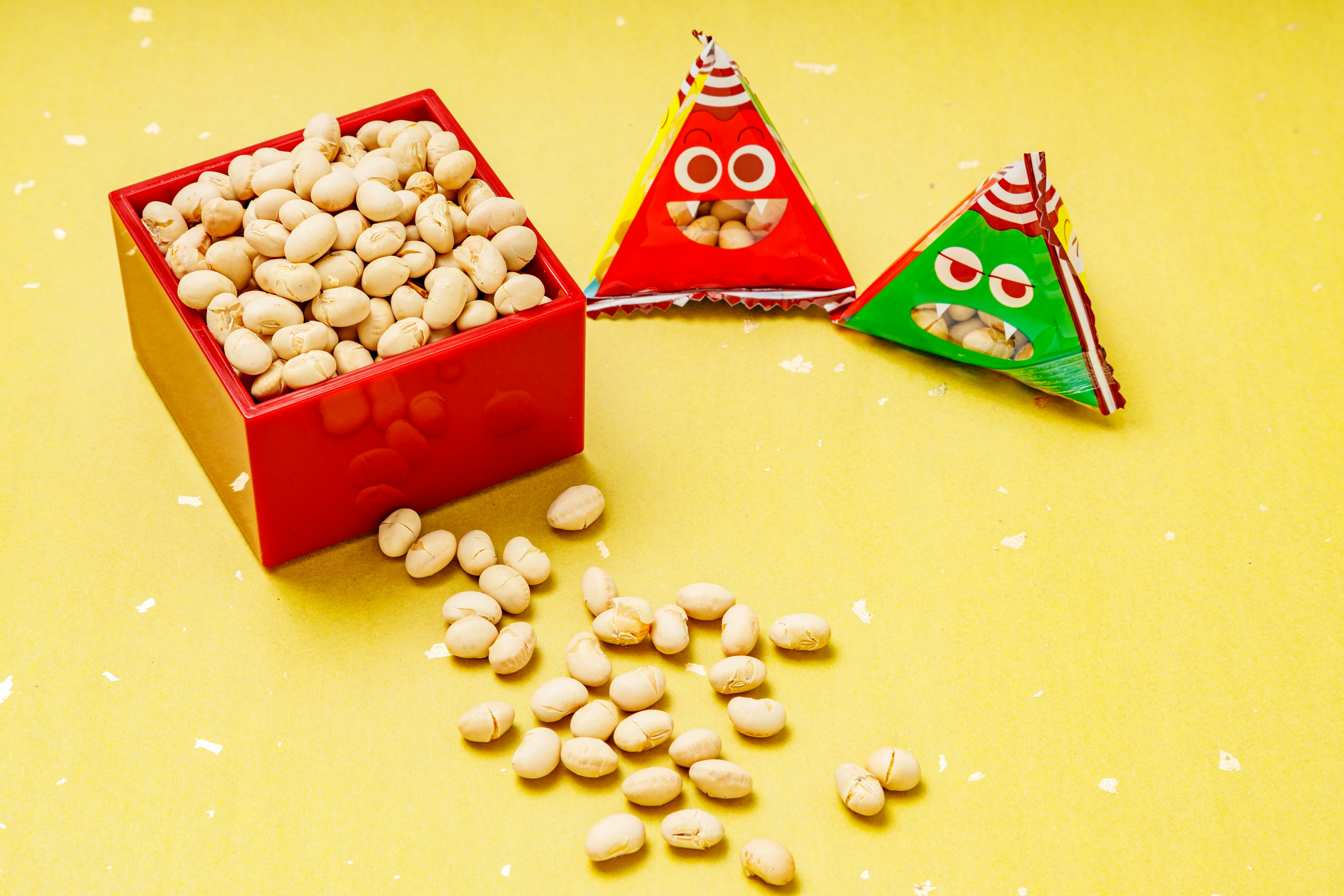 Image featuring a red box filled with white candies and triangular character chocolates on a yellow background