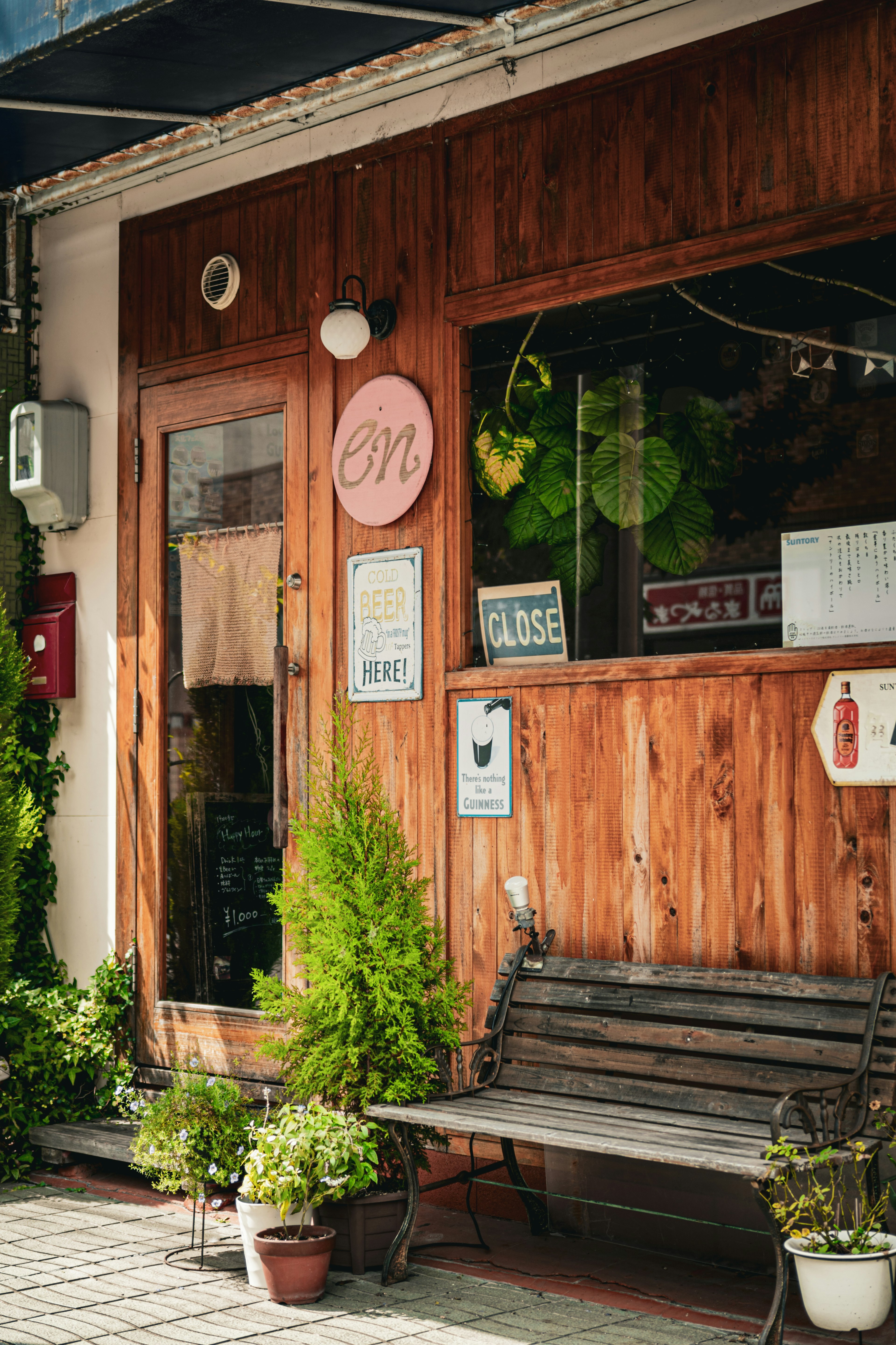 Extérieur d'un café avec des murs en bois et des plantes vertes