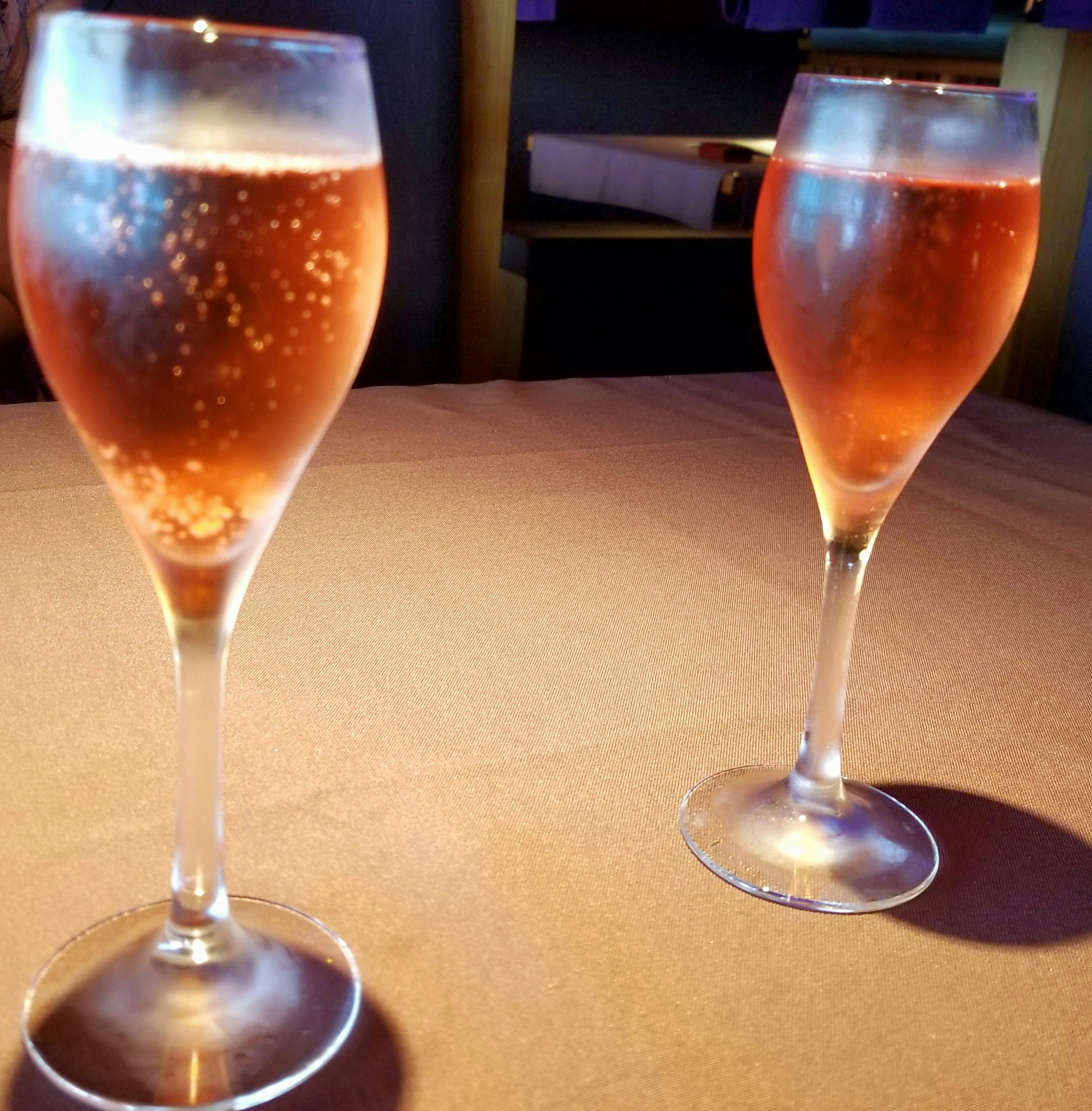 Two champagne glasses filled with sparkling rosé wine