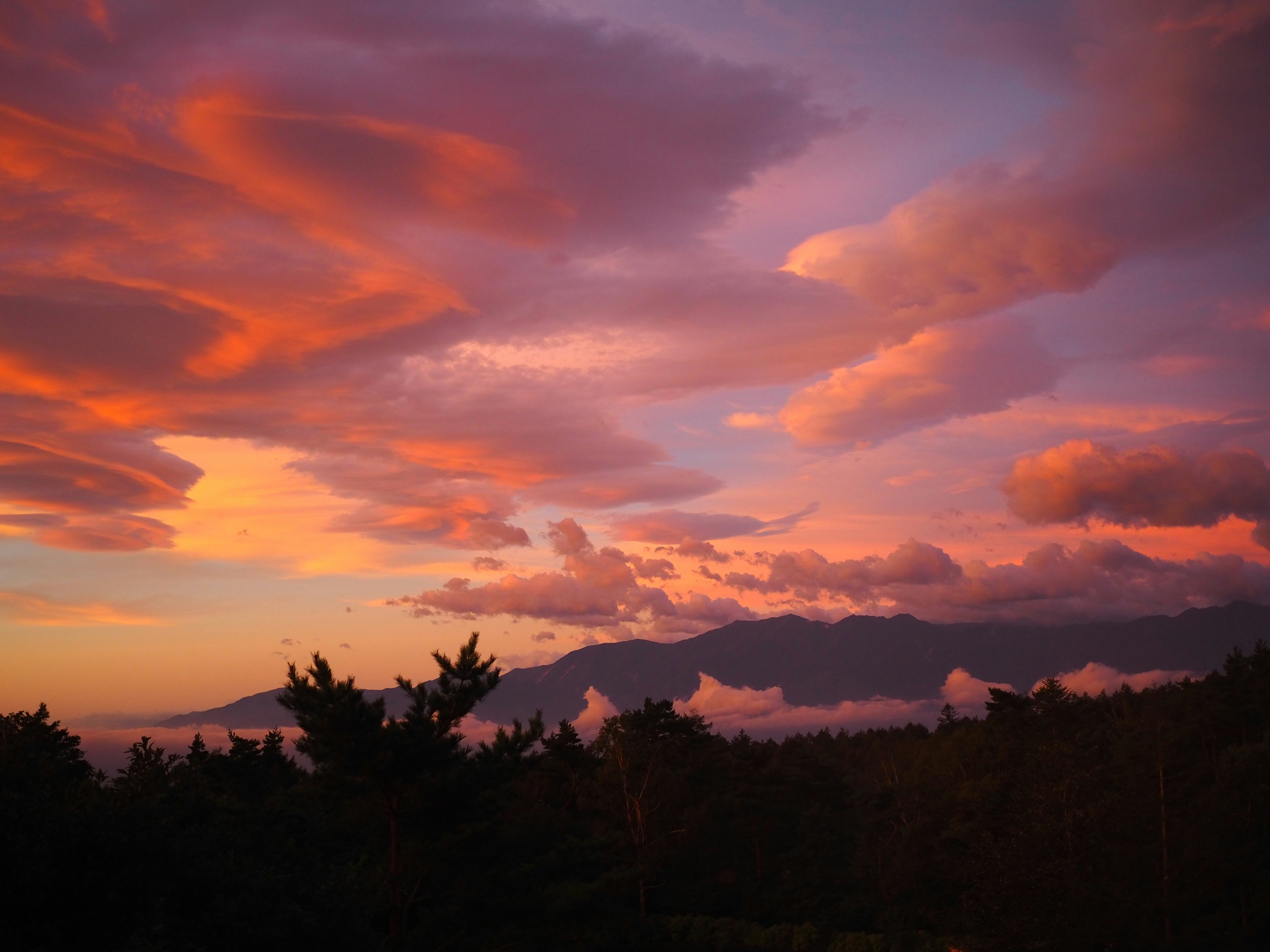 Colorful clouds in a beautiful sunset sky with mountain silhouettes in the background