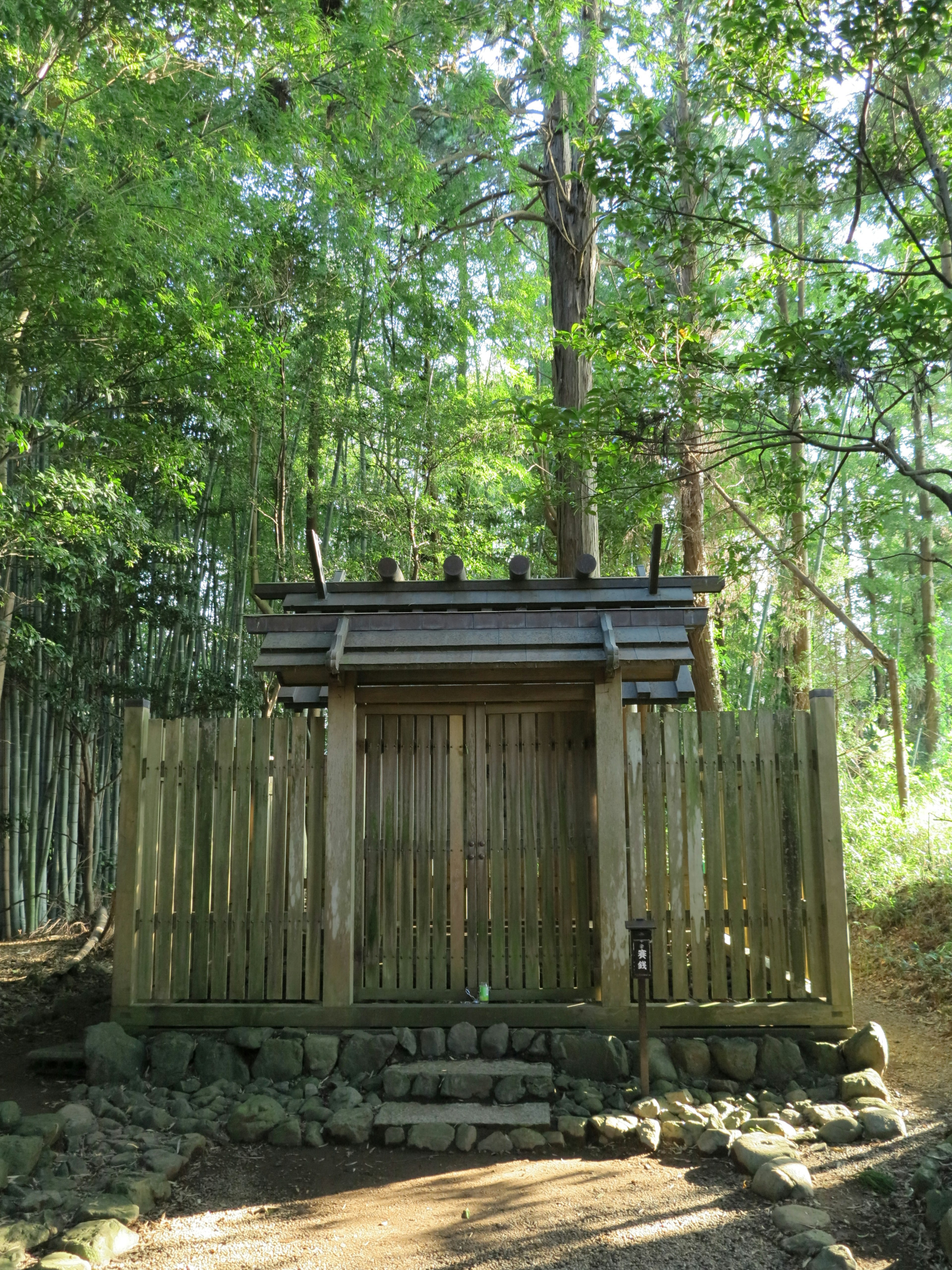 Una piccola struttura in legno simile a un santuario circondata da alberi verdi