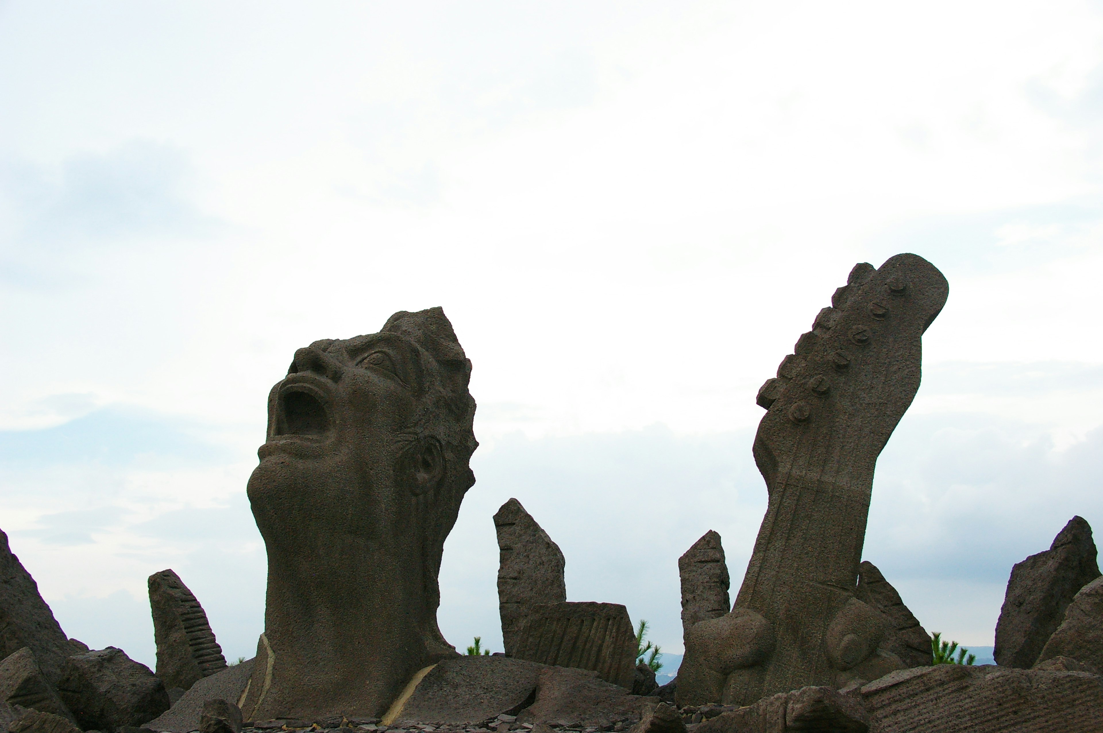 Stone sculpture of a human face and feet looking up at the sky