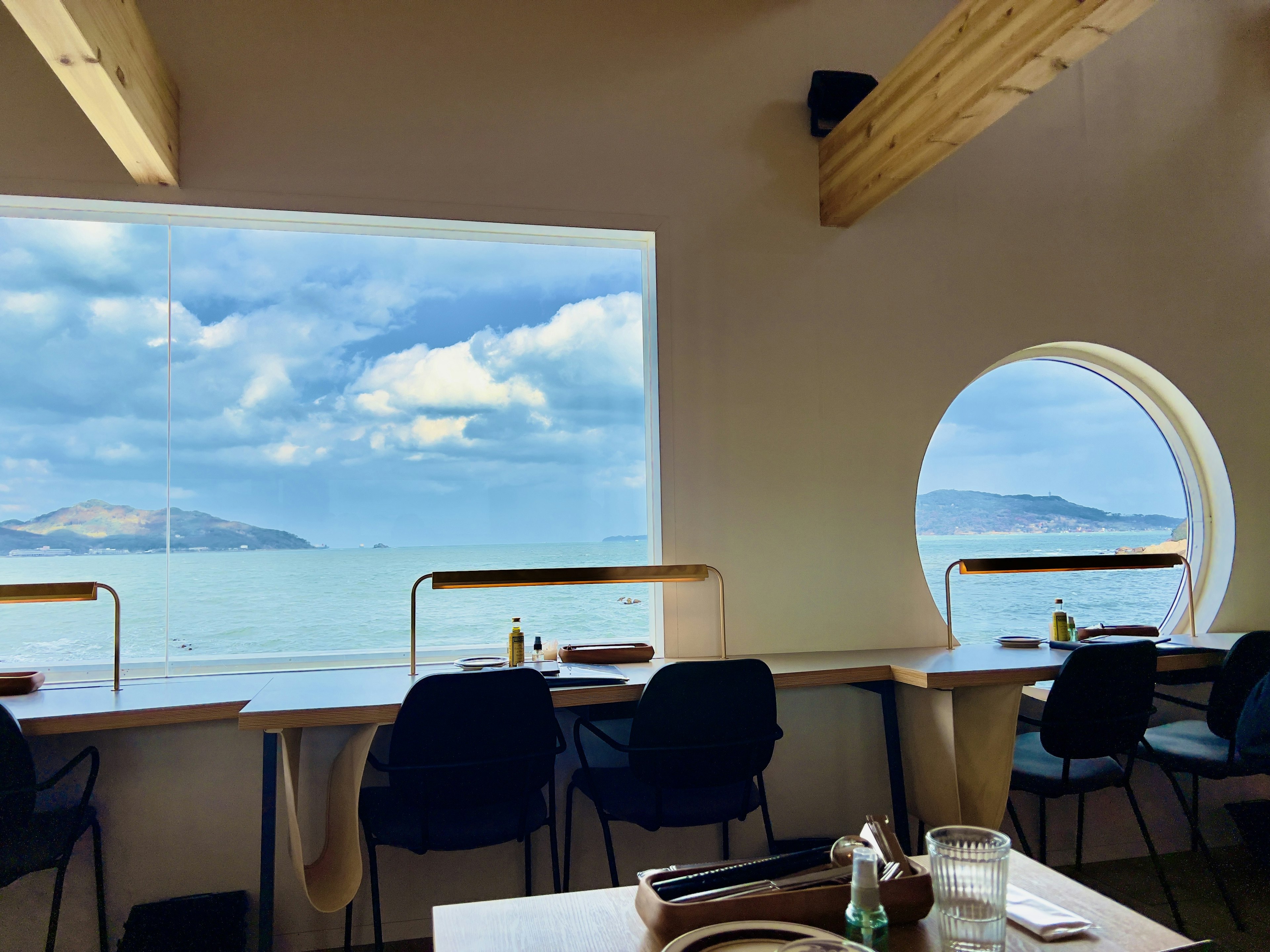 Interior restoran modern dengan pemandangan laut dan pulau di bawah langit biru