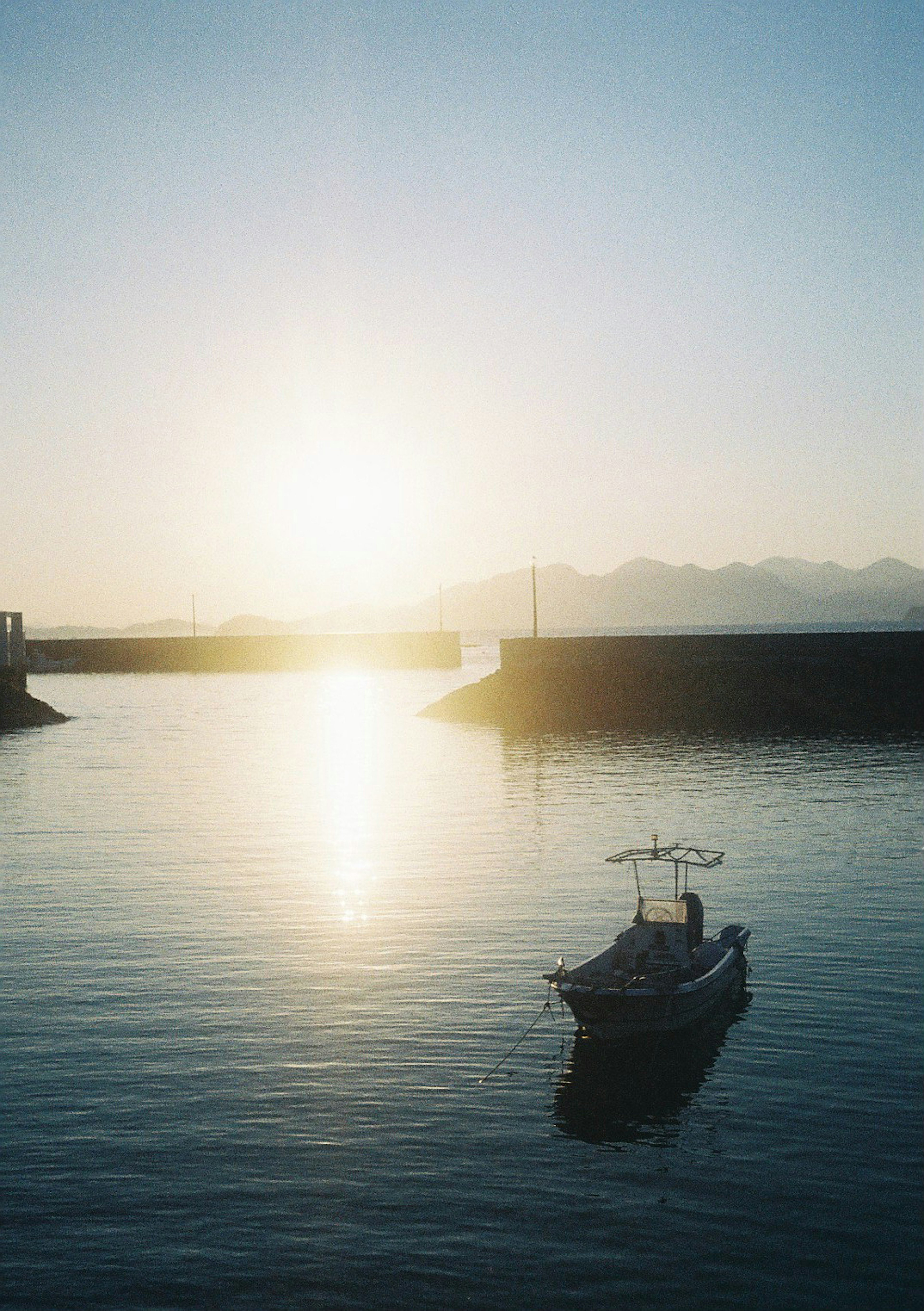 穏やかな海に浮かぶ小さなボートと輝く朝日