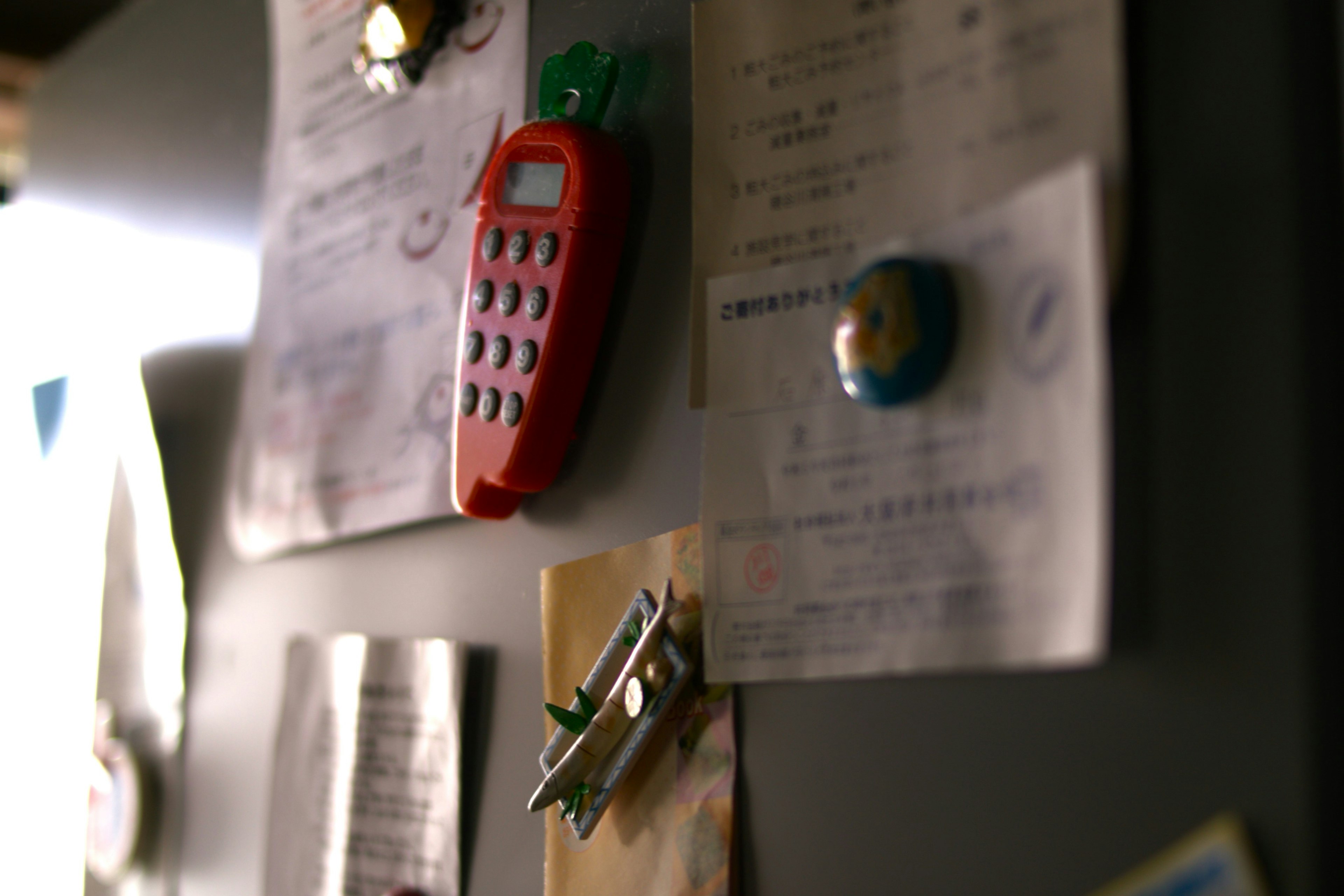 Teléfono móvil rojo y notas pegadas en la puerta del refrigerador