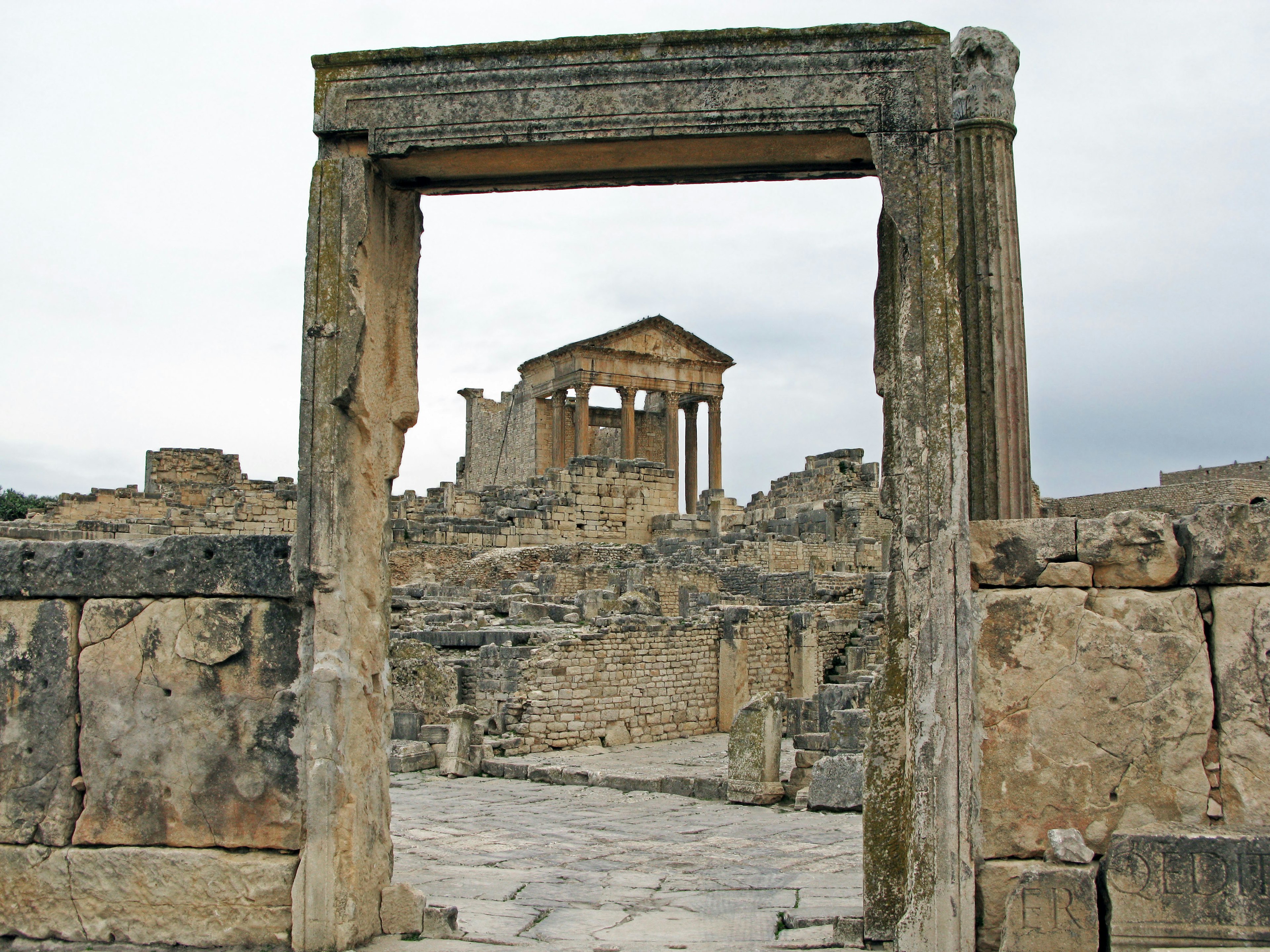 Voûte menant aux ruines d'un temple ancien sous un ciel nuageux