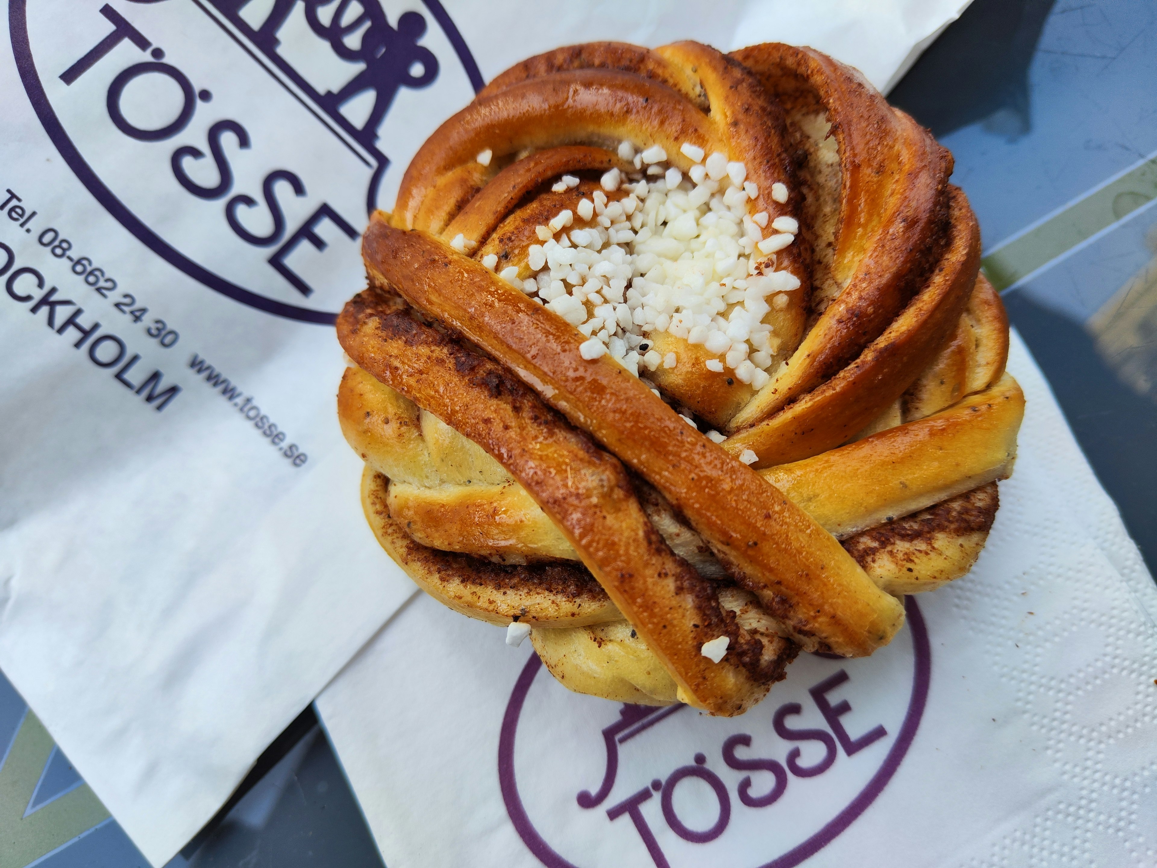 Swedish cinnamon roll styled pastry placed on a napkin with TÖSSE logo