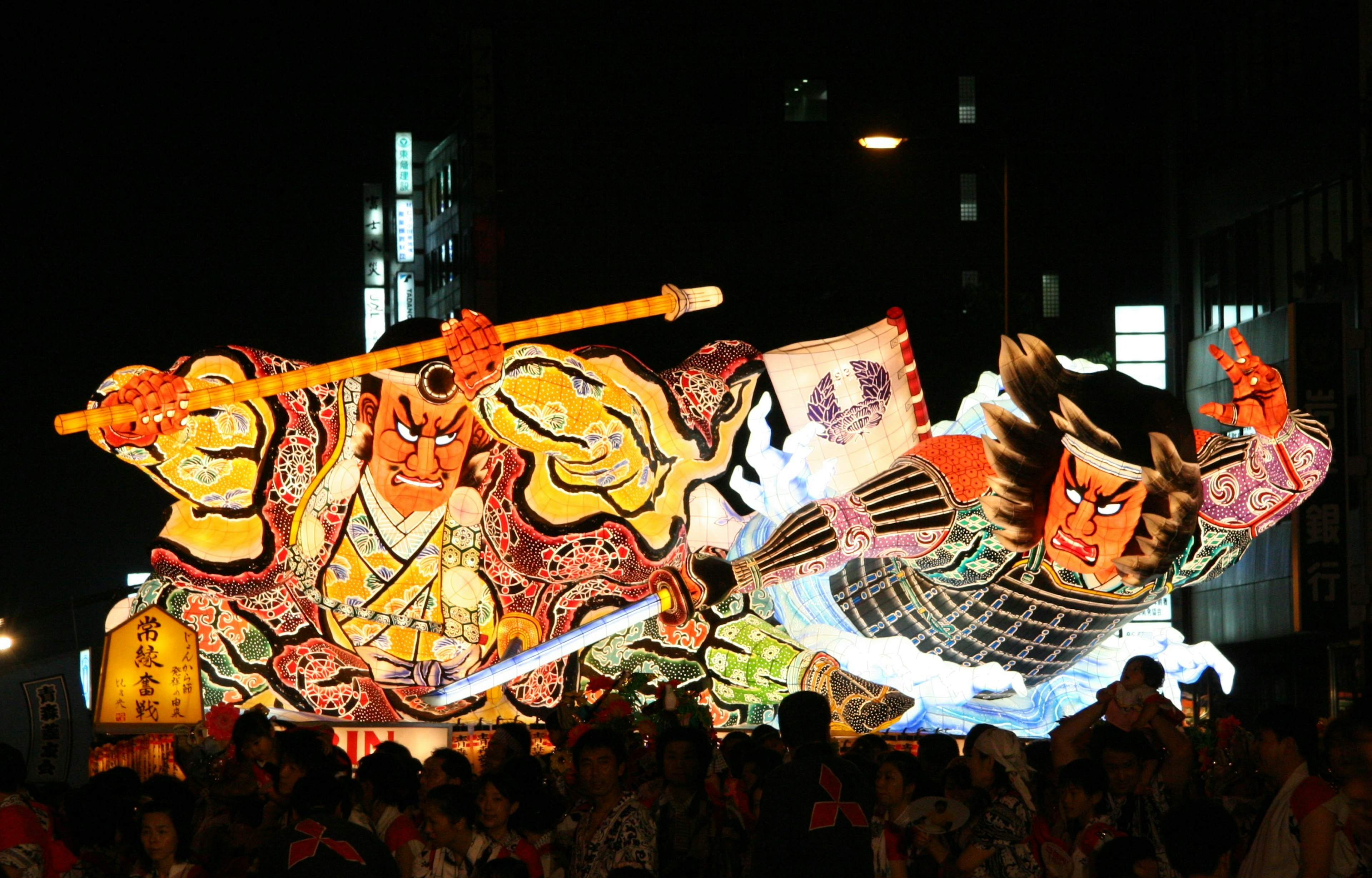 Ein großer, farbenfroher Wagen, der während eines Nachtfestivals präsentiert wird