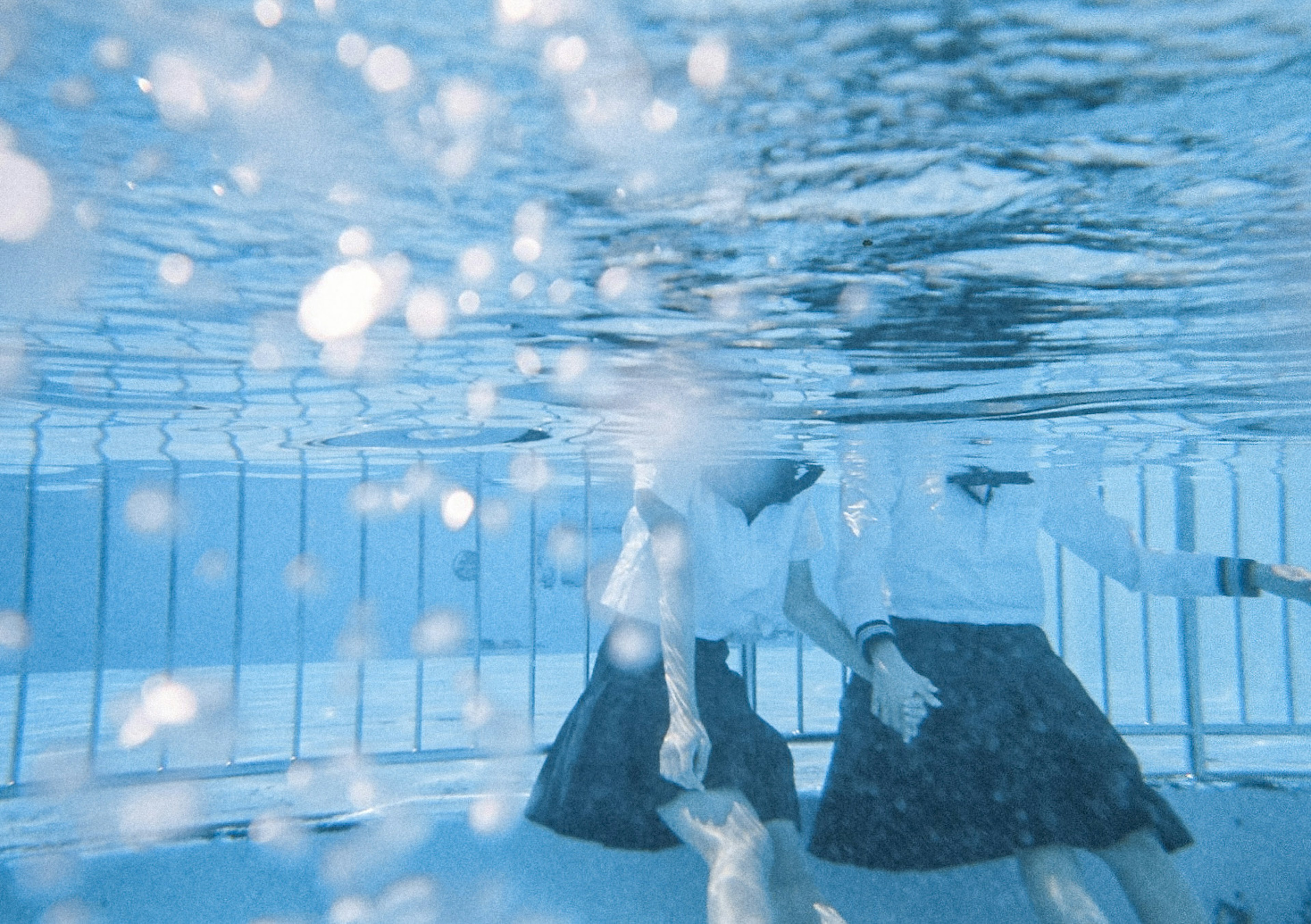 水中で遊ぶ二人の学生が見える青い水の画像