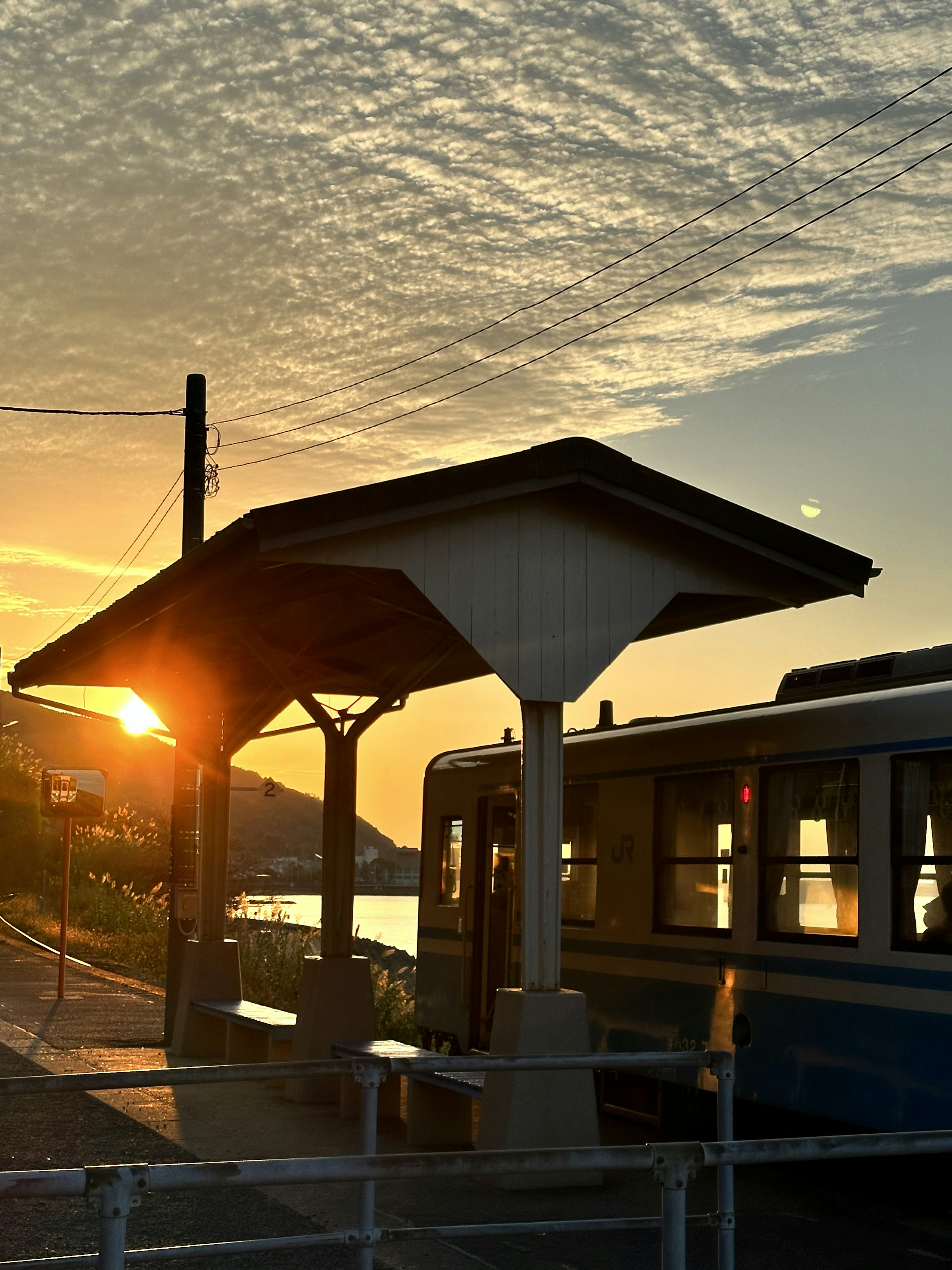 Silhouette of train station platform and train bathed in sunset light