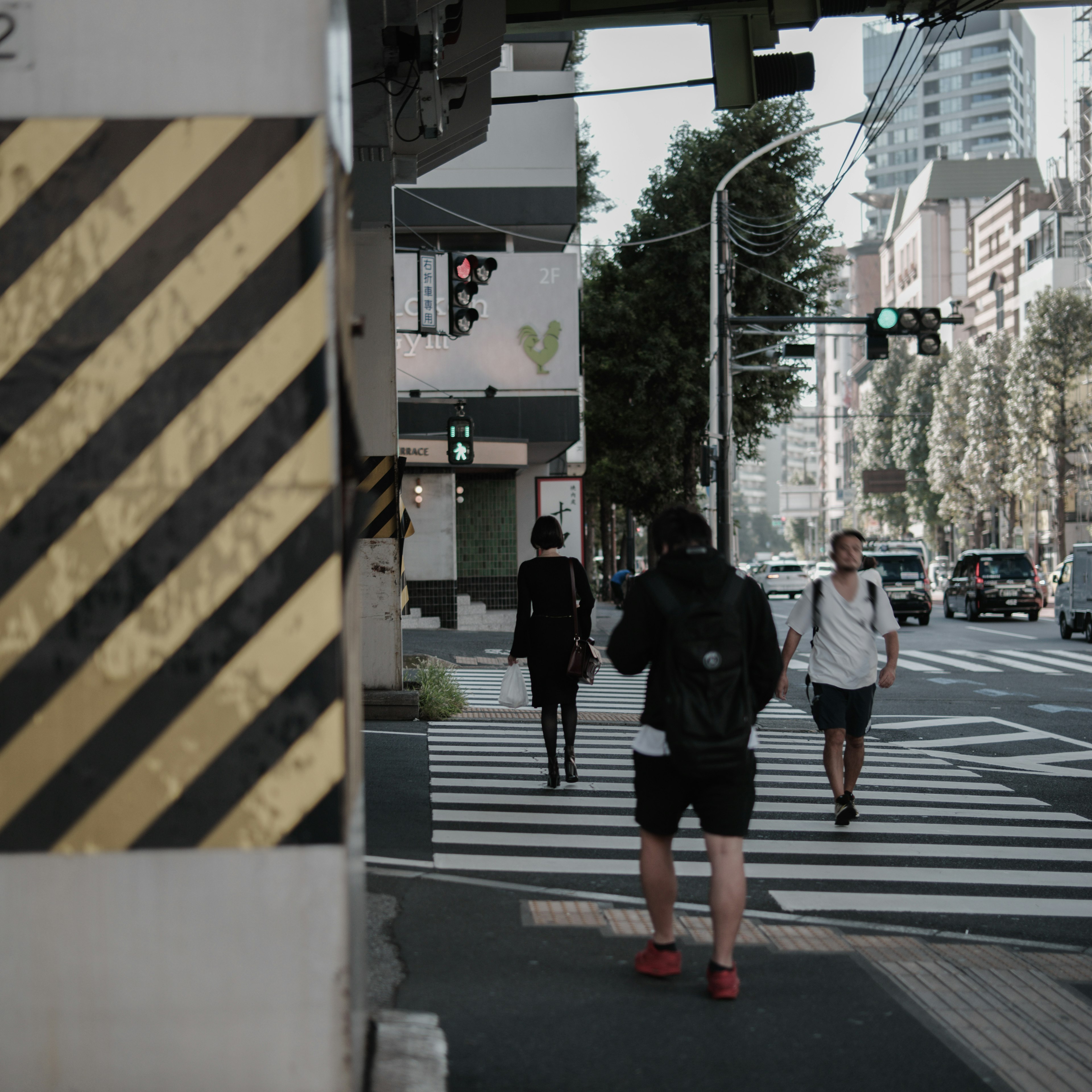 街の交差点で信号待ちの人々と黄色と黒の警告標識