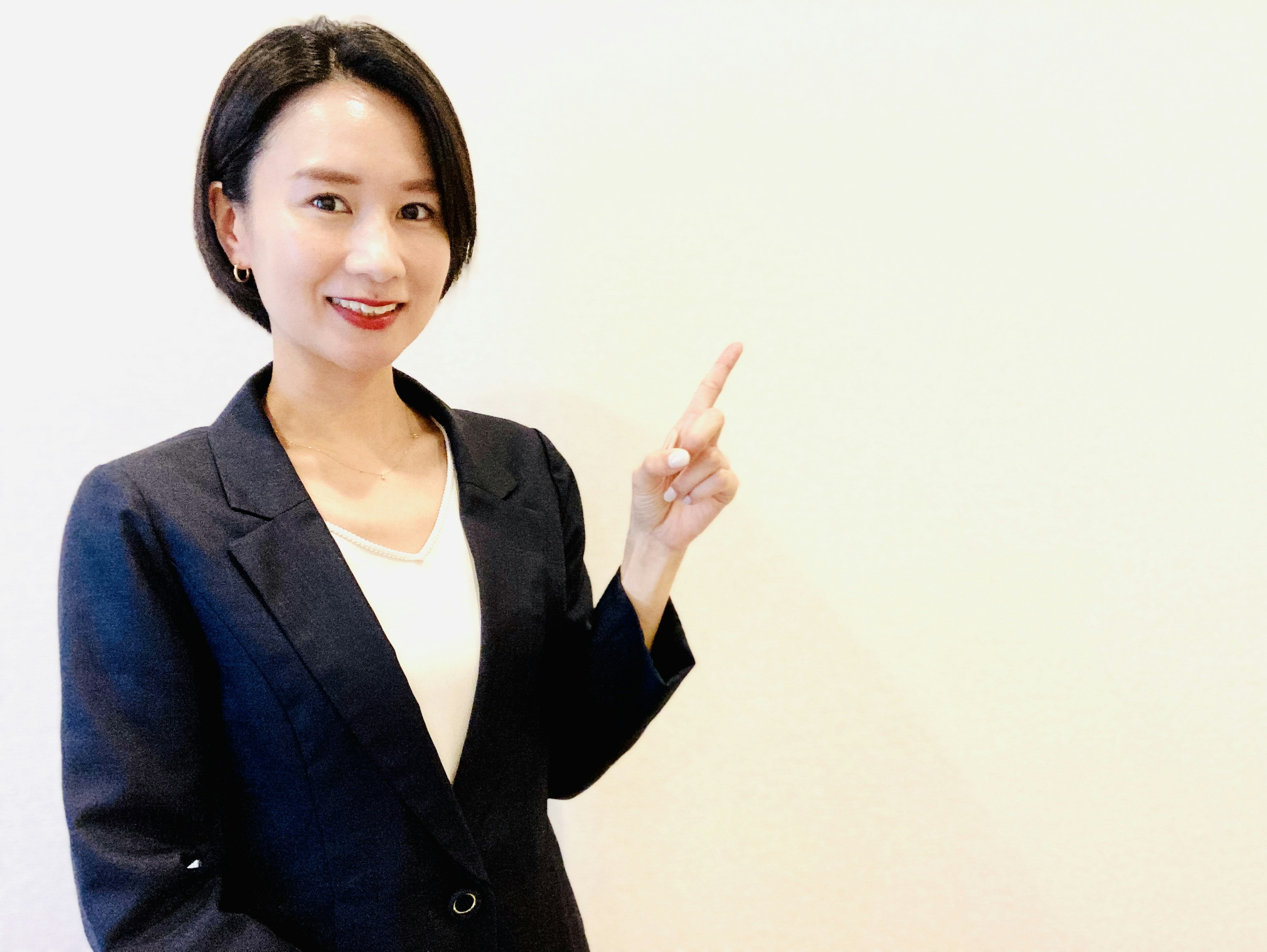 A woman in a suit pointing with a simple background