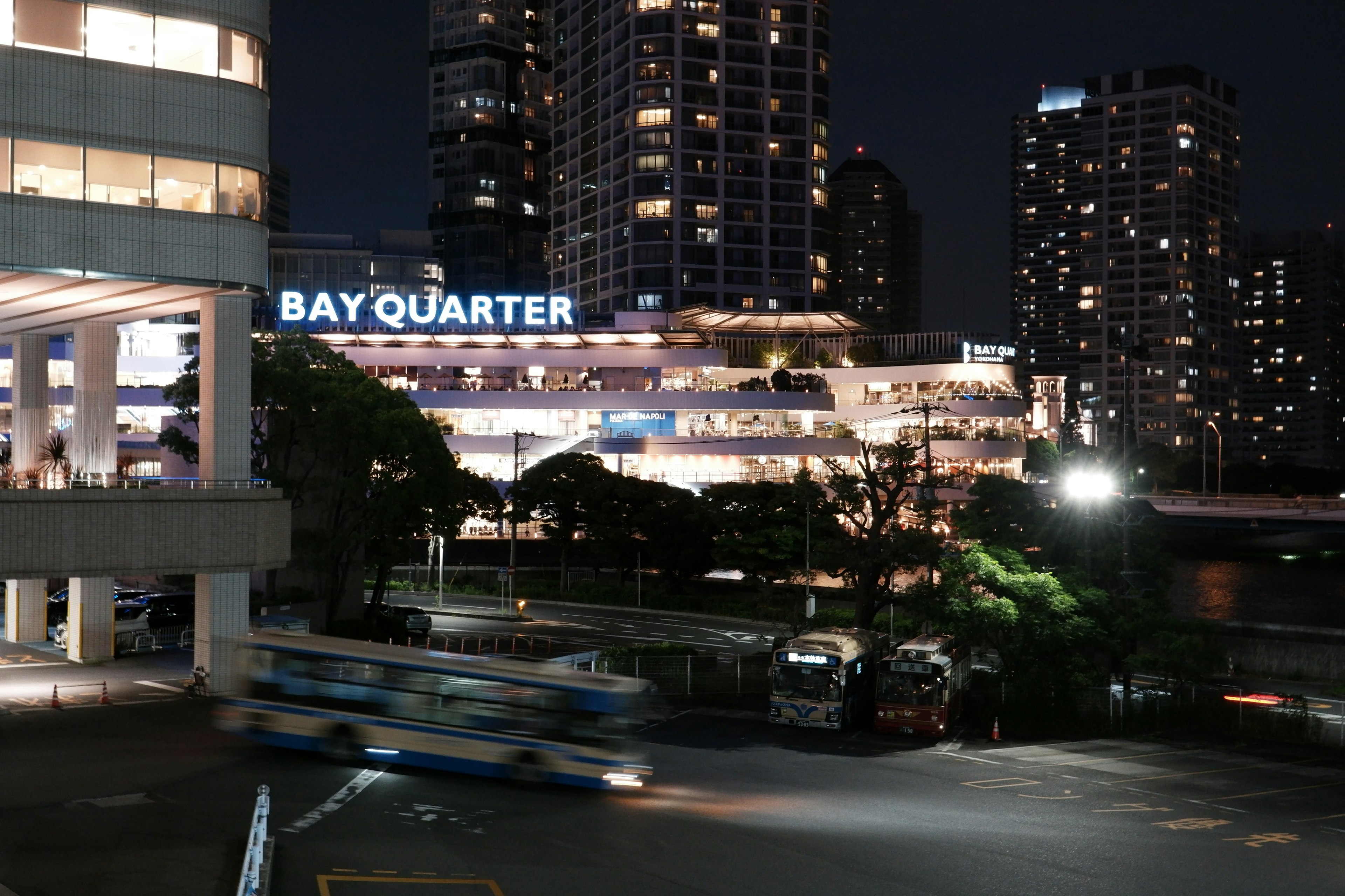 Vista nocturna del letrero Bay Quarter y rascacielos en la ciudad